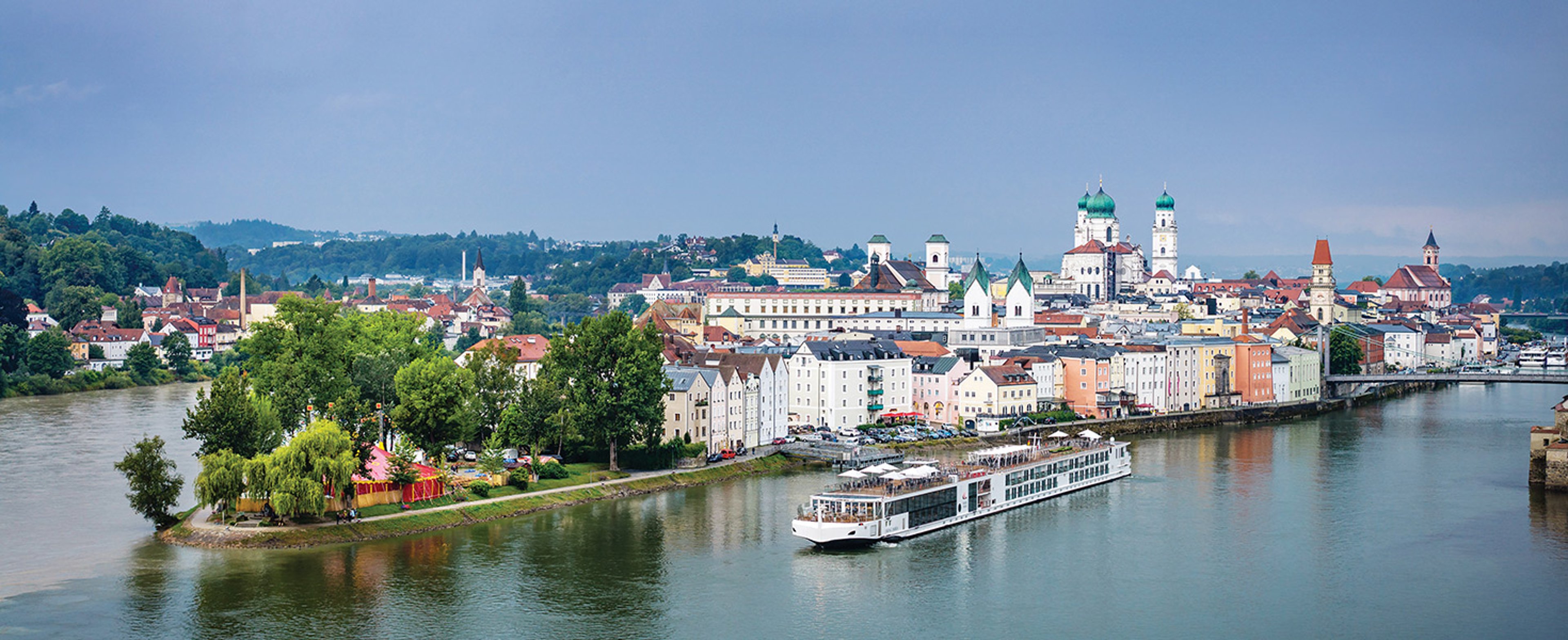 The image shows a Viking Longship cruising past the historic old town of Passau, Germany, known as the "City of Three Rivers" where the Danube, Inn, and Ilz meet
