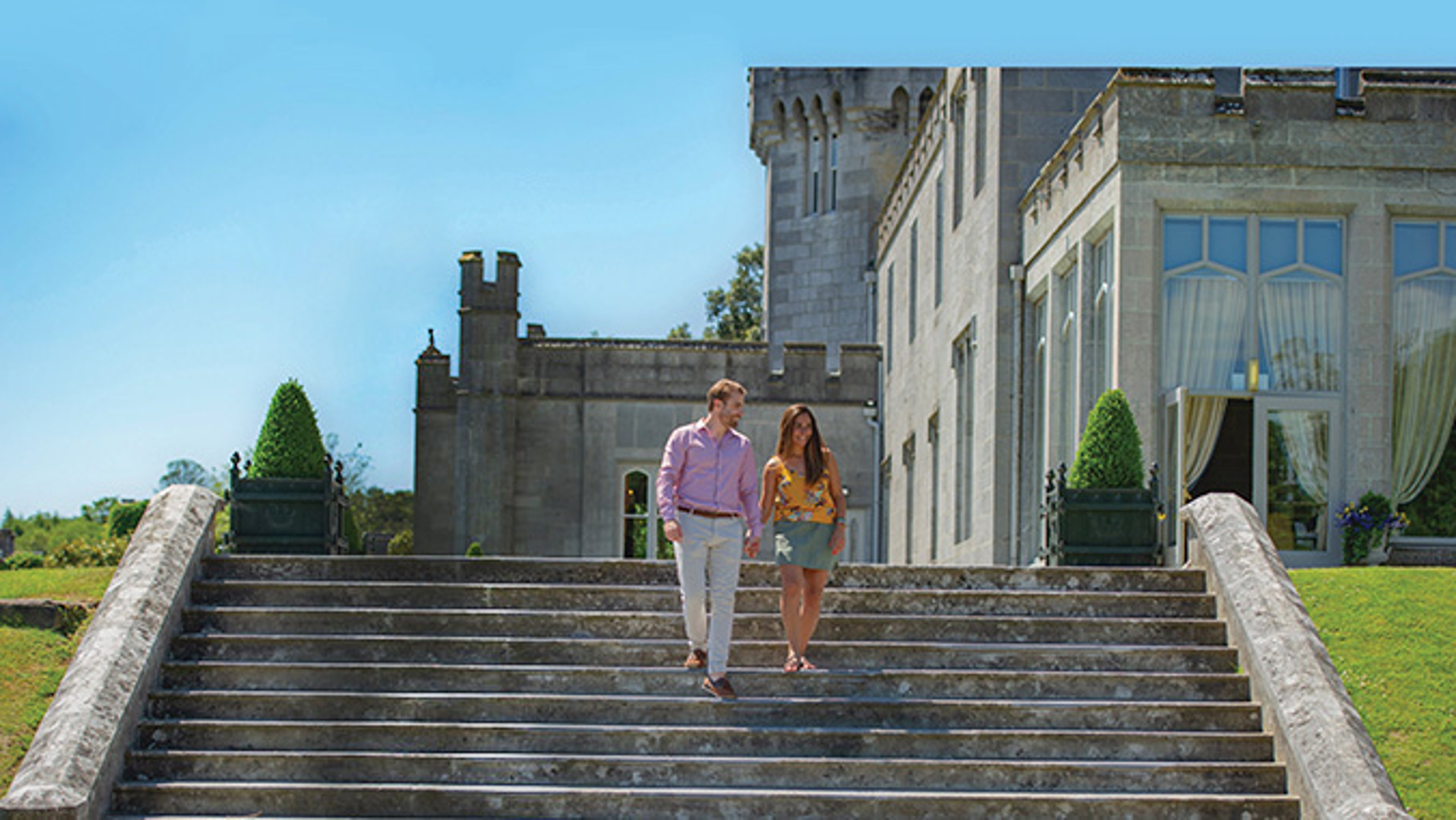 Couple walking down steps of Dromoland Castle on sunny day