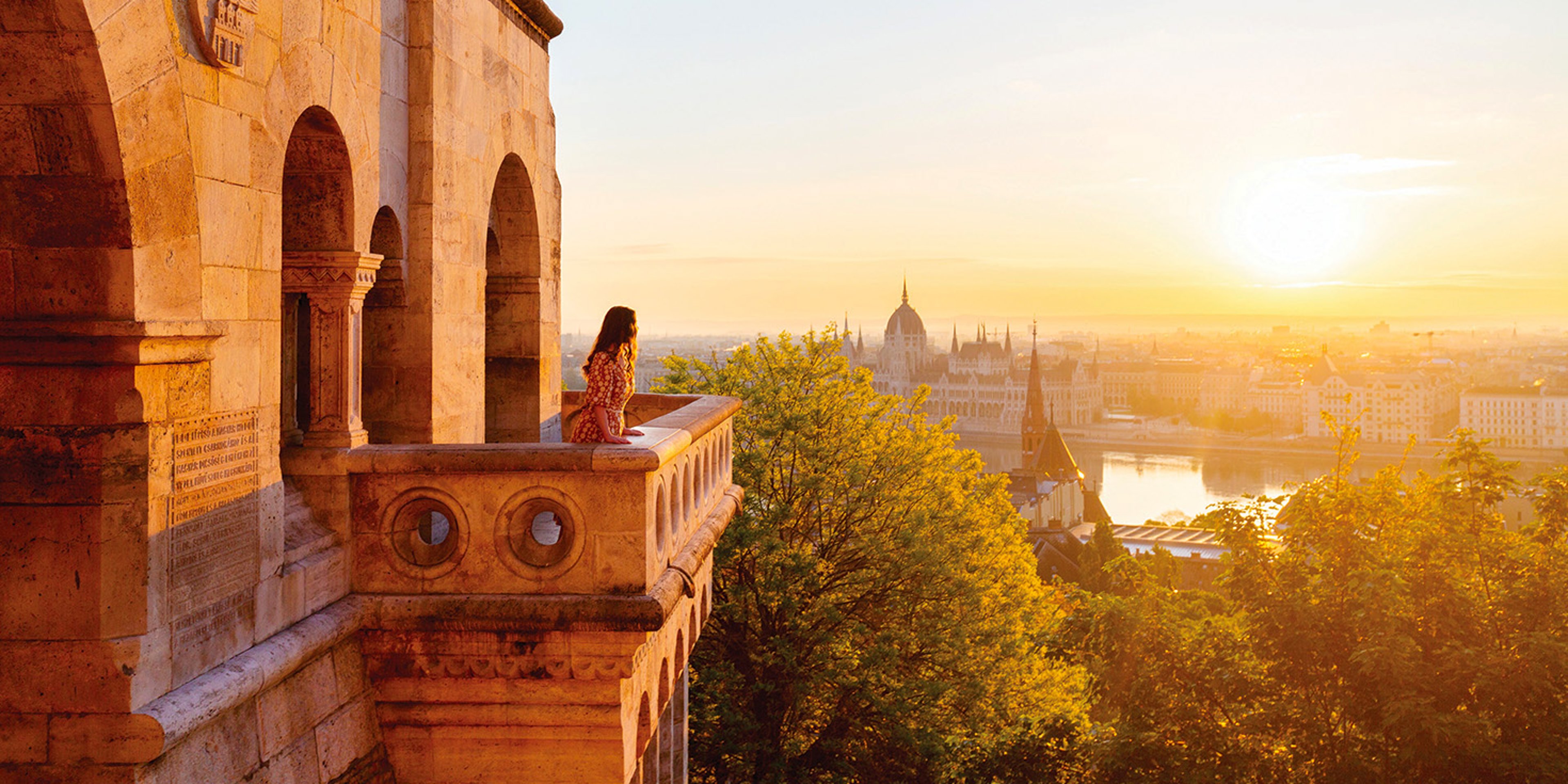 Woman on balcony of Fisherman's Bastion overlooking Budapest, Hungary at sunset