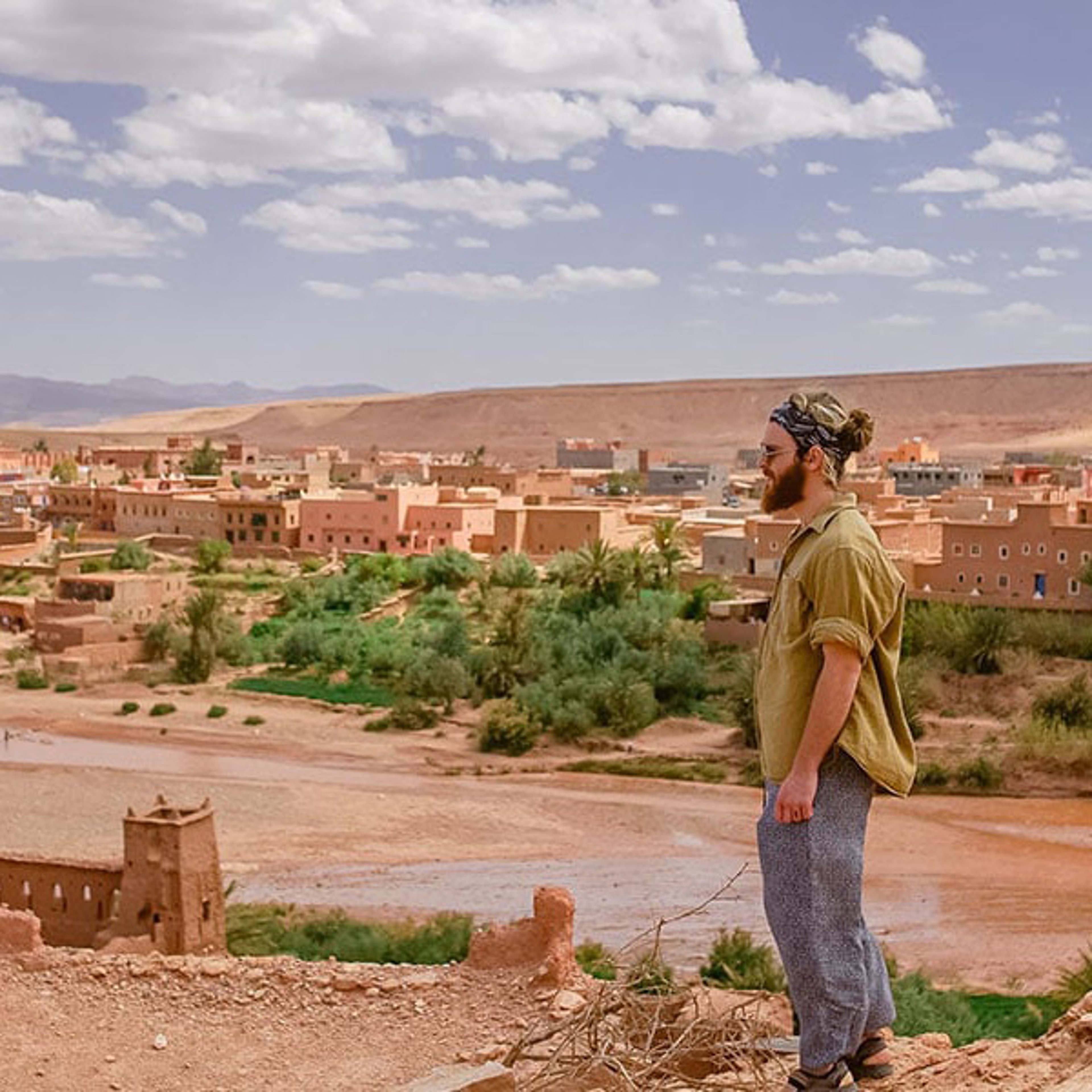Young male tourist with sunglasses overlooking desert village of Aït Benhaddou, Morocco 