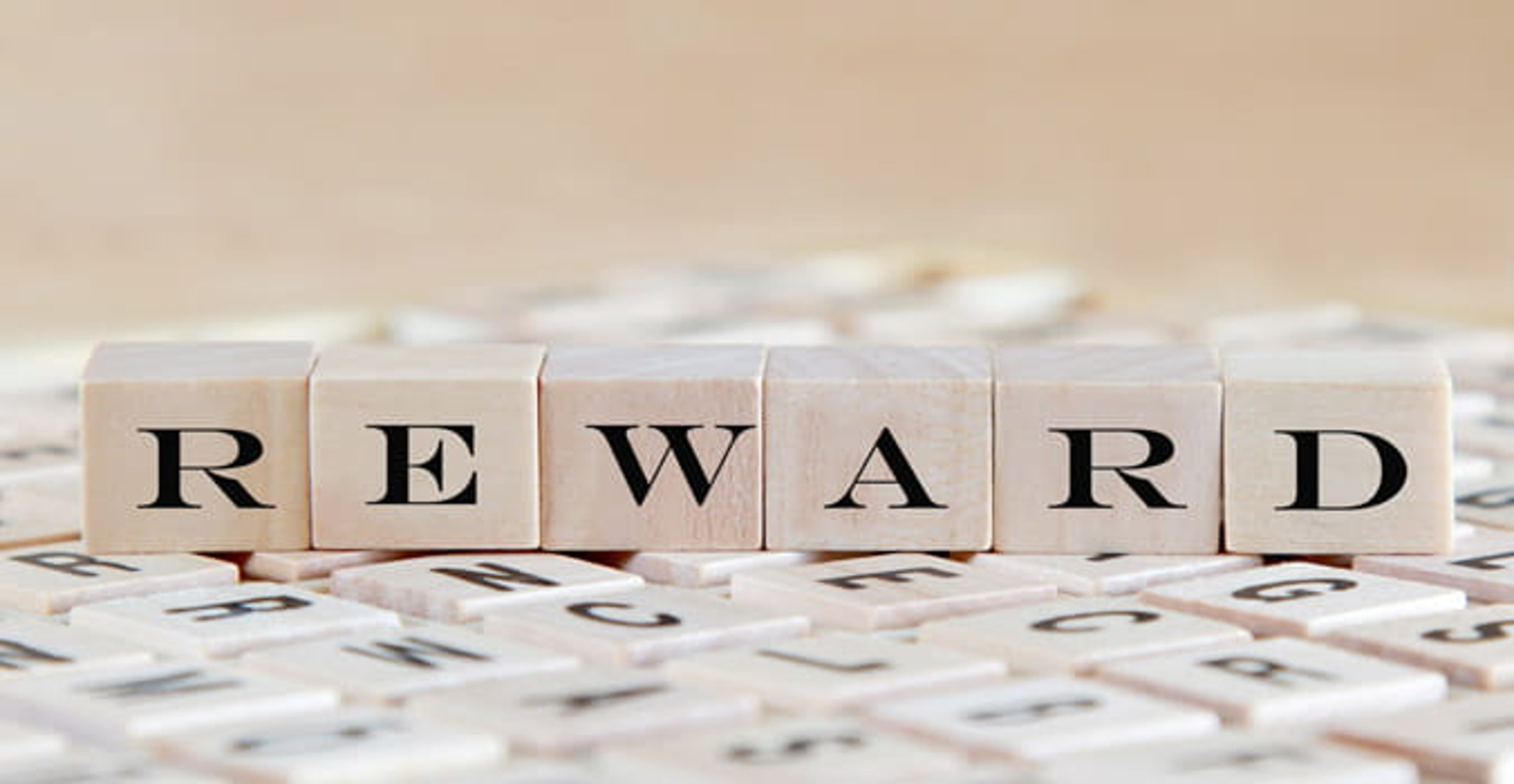 Wooden tiles spelling out REWARD on a table