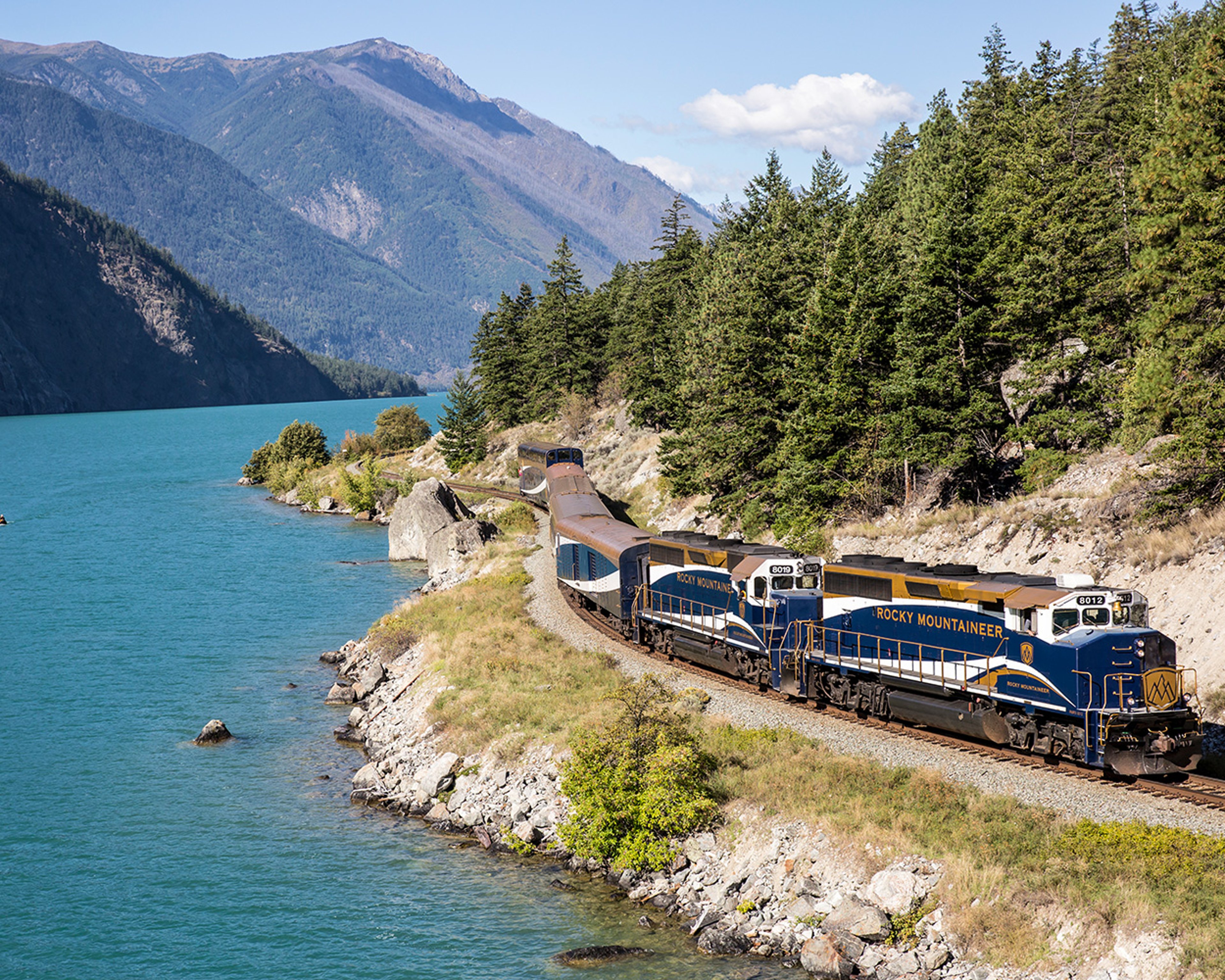 Exterior of Seton train winding through Rocky Mountains by lake