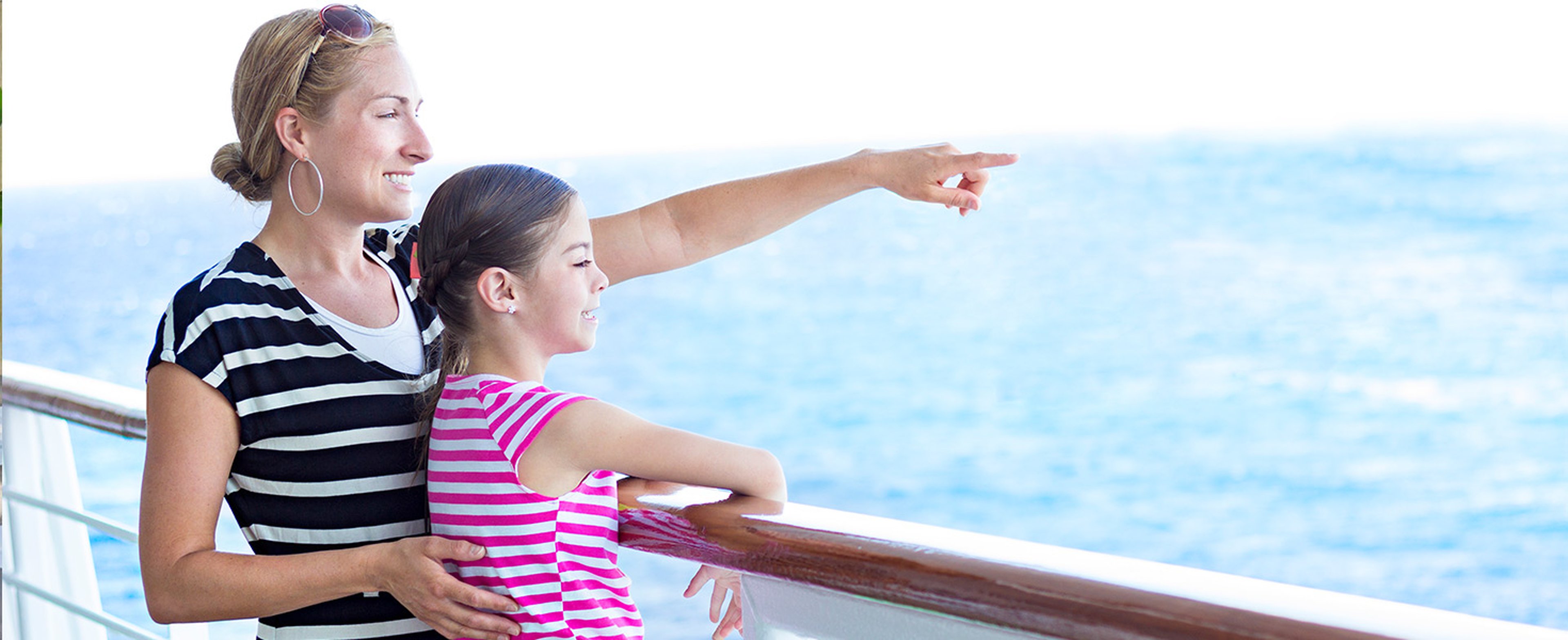 Mom pointing scenery out to daughter from deck of a cruise ship