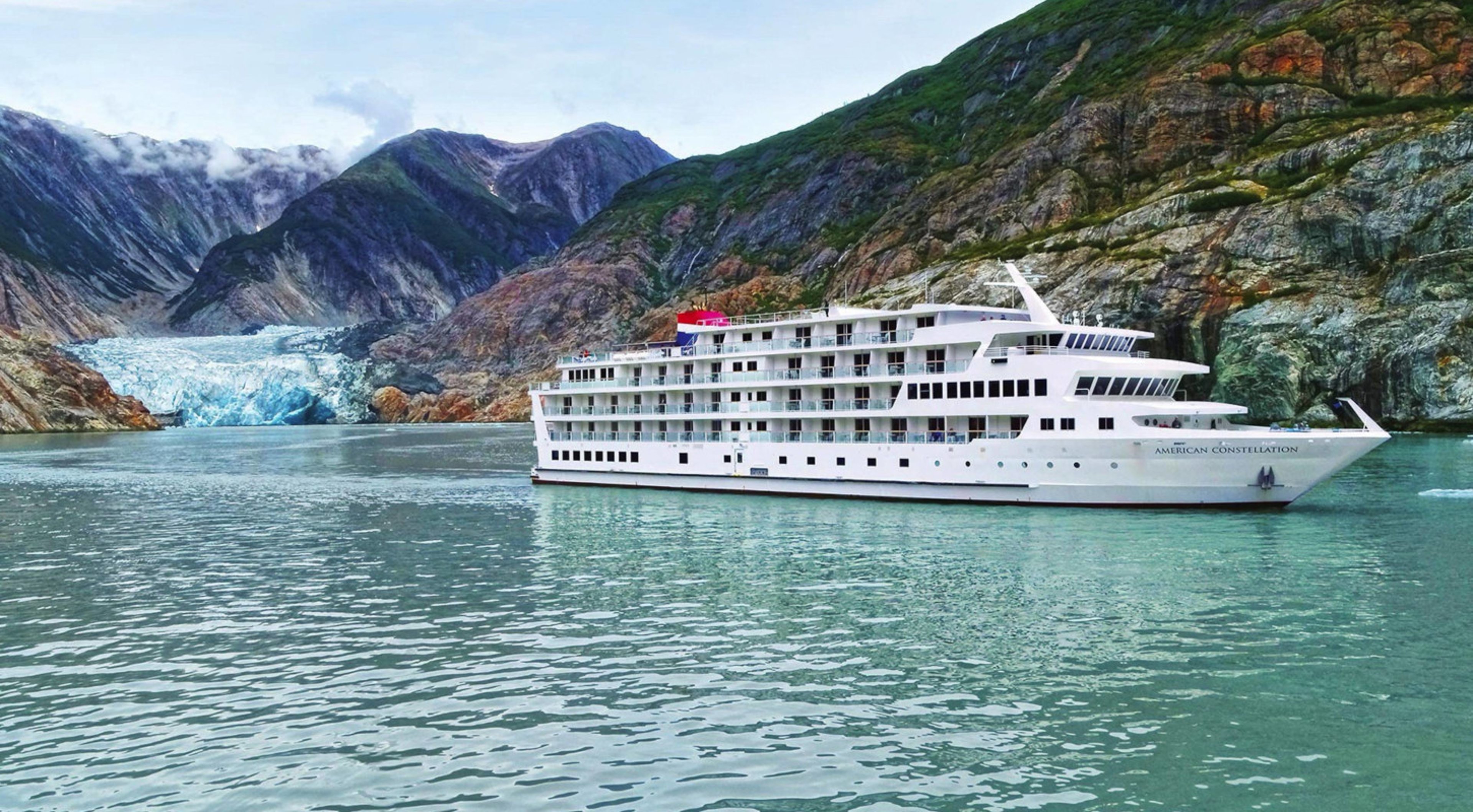 American Cruise Line American Constellation ship sailing through clear blue glacial waters 