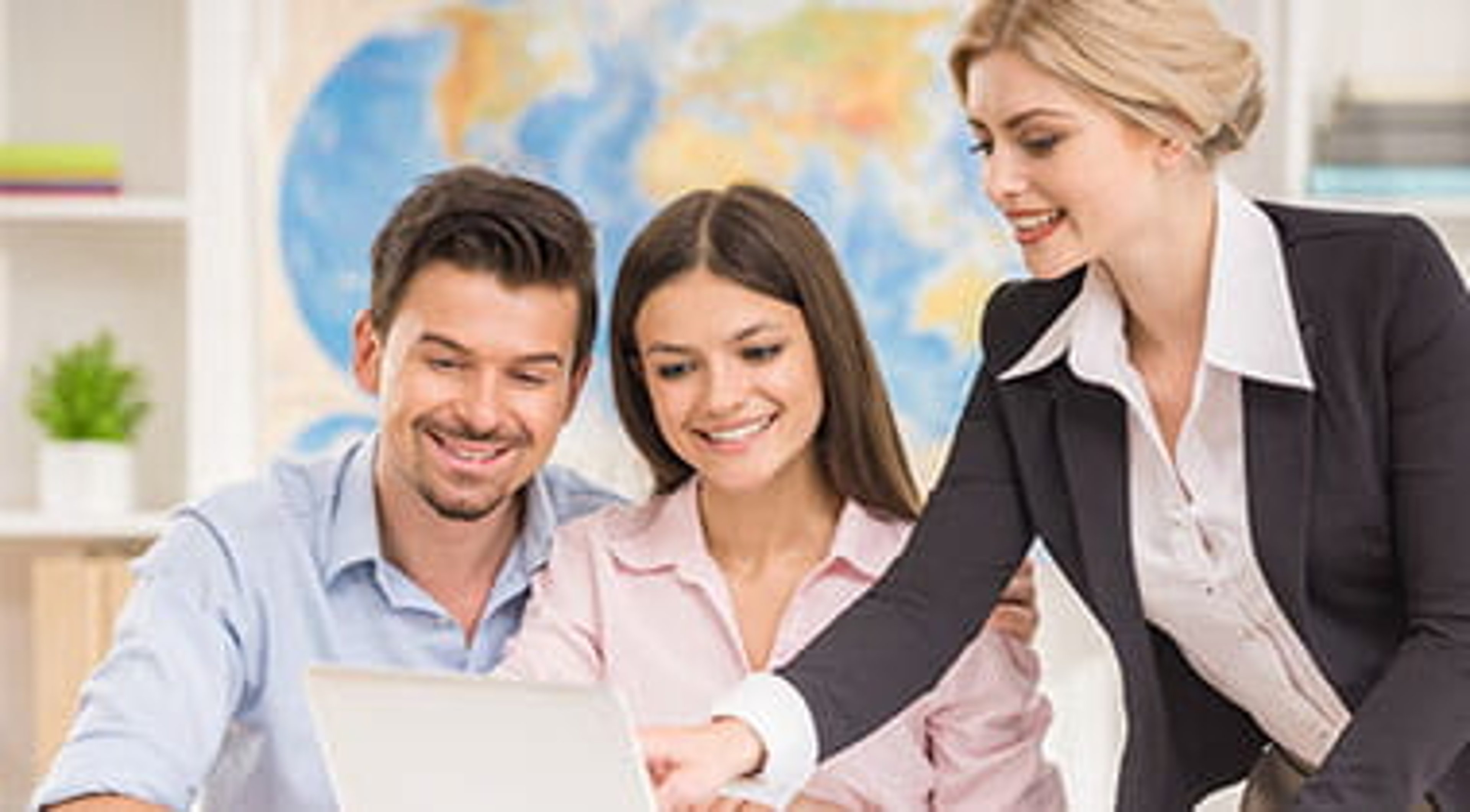 A couple speaking with a travel agent looking at a computer screen