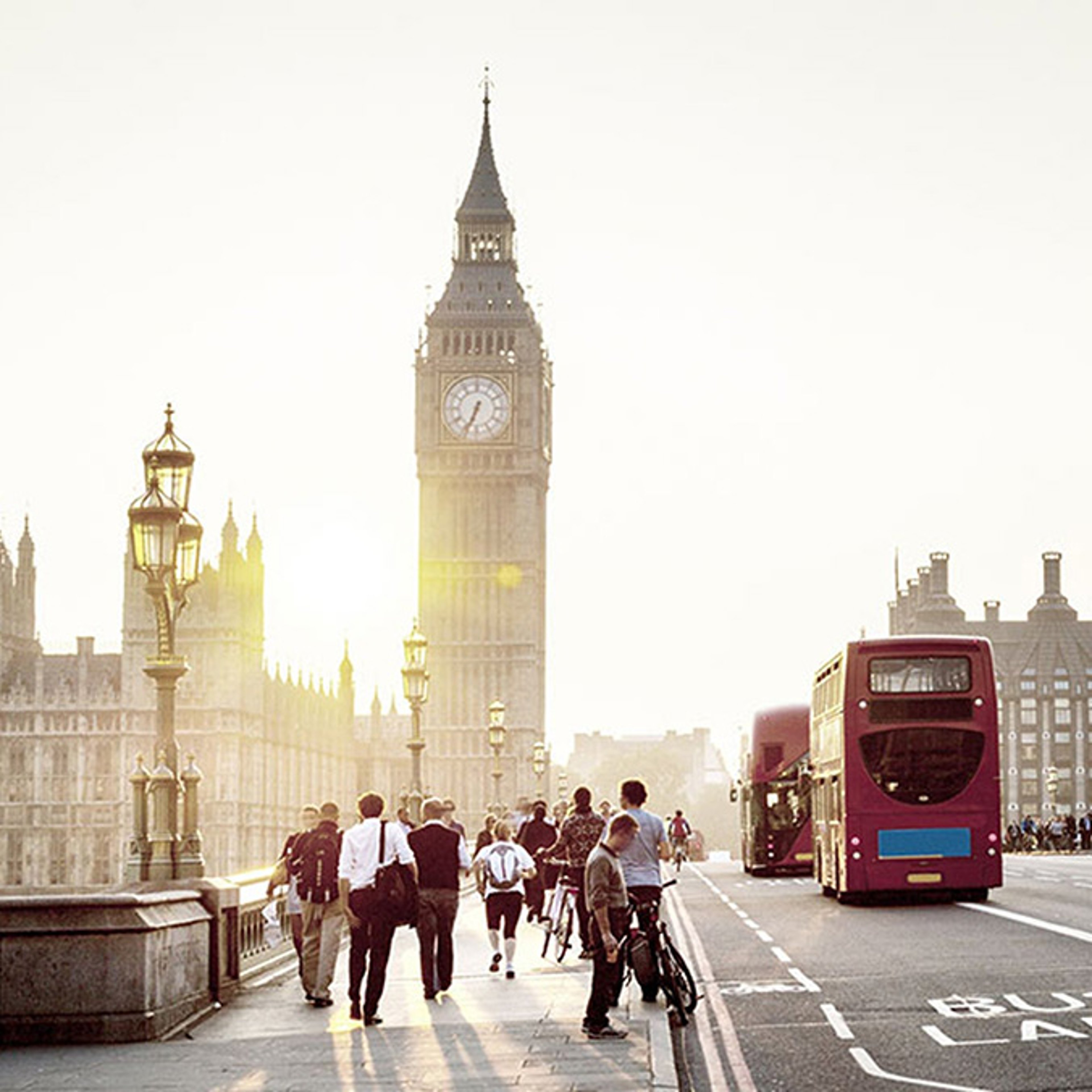 A view of Big Ben and pedestrians in London, alongside double decker buses.