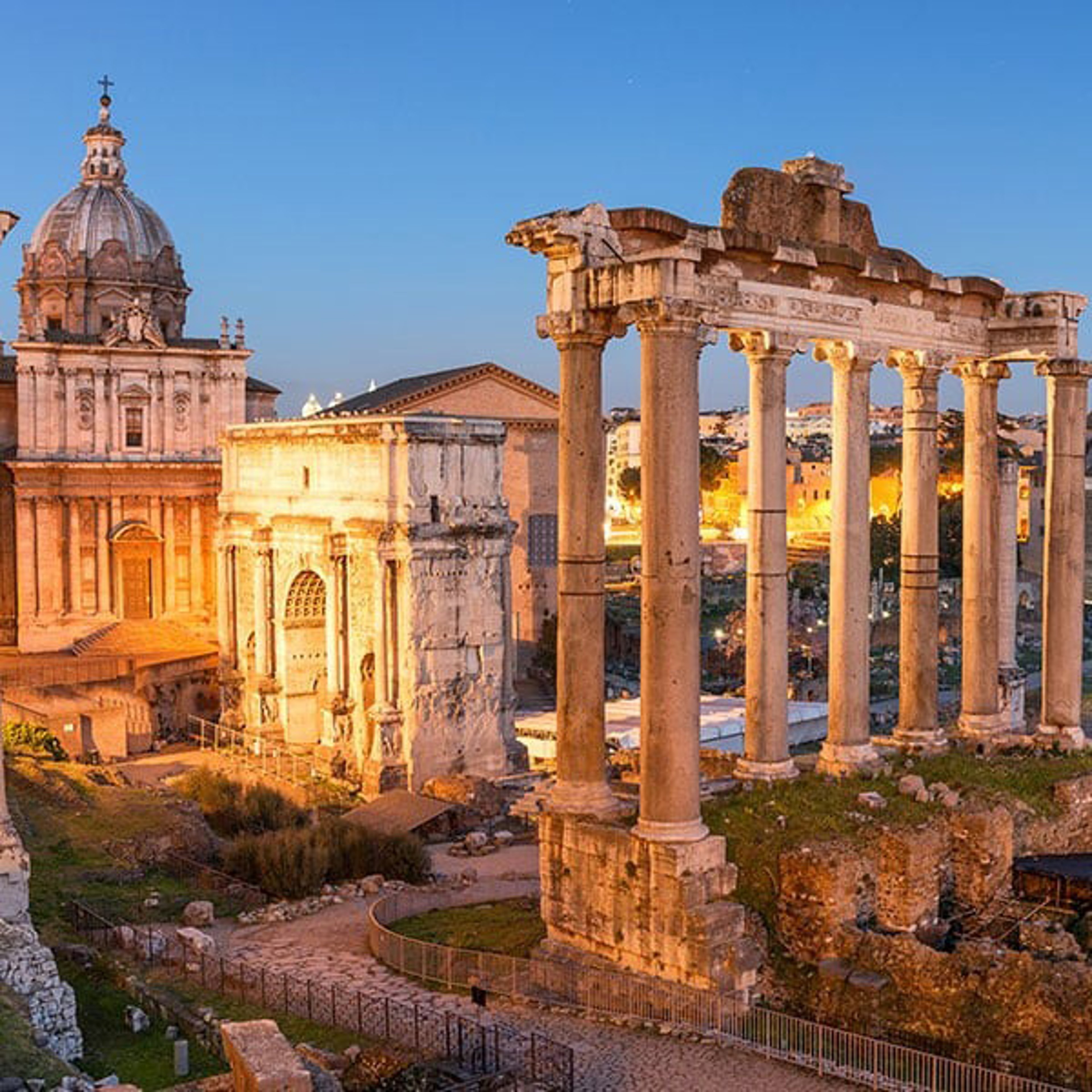 Roman Forum at dusk, showcasing ancient illuminated ruins and architectural elements under a twilight sky.