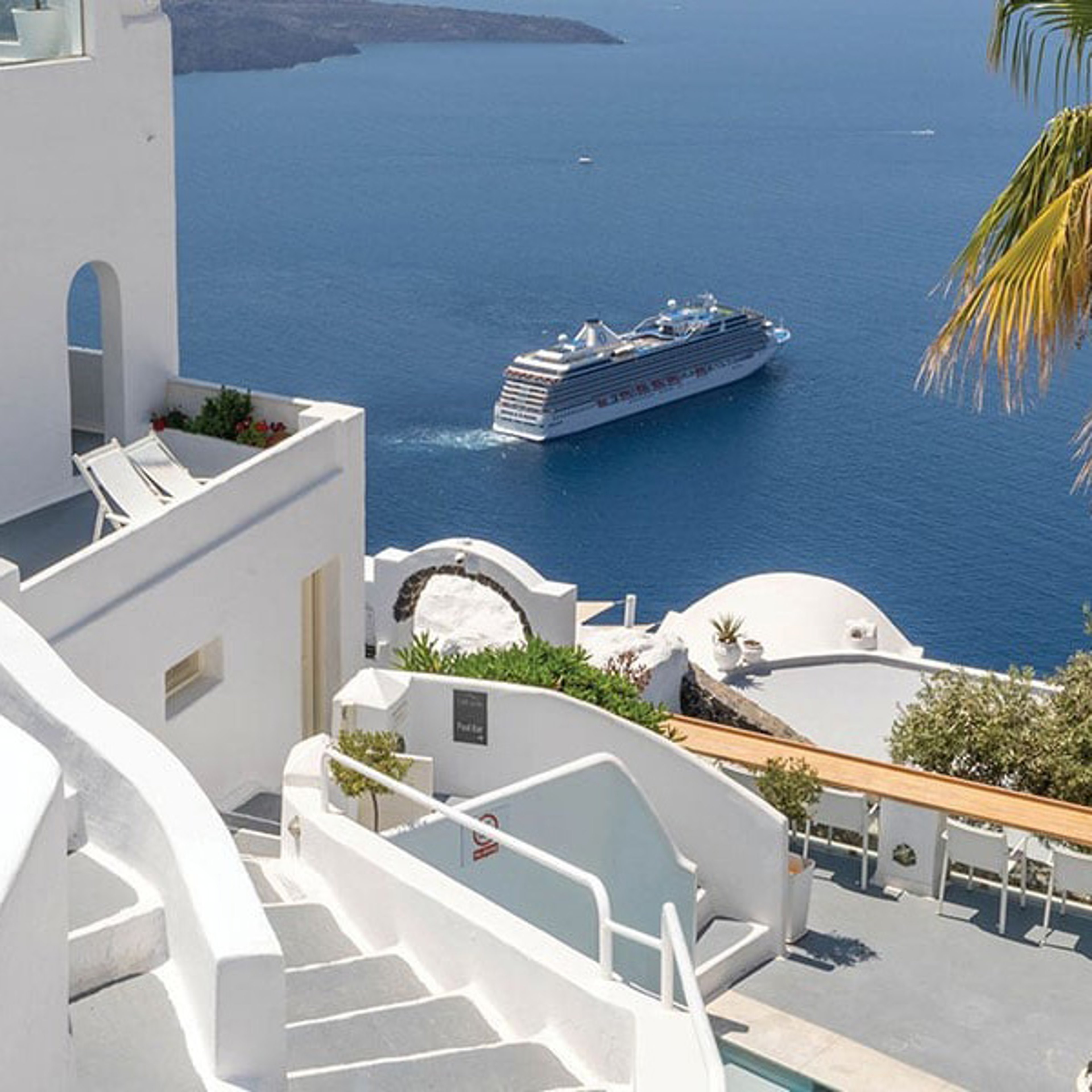 View of white buildings and a cruise ship in the blue Aegean Sea, Santorini, Greece.