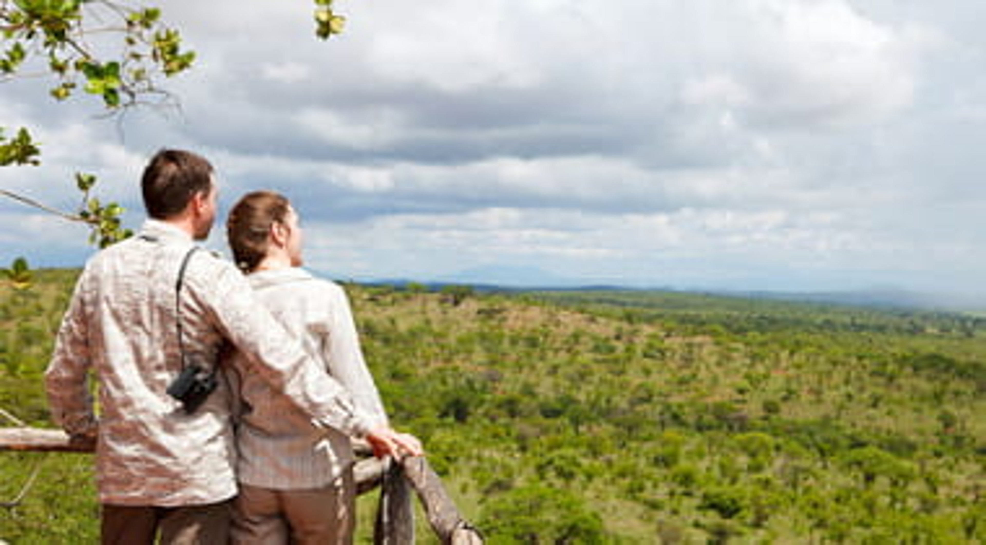 Couple on safari vacation looking to savanna from balcony