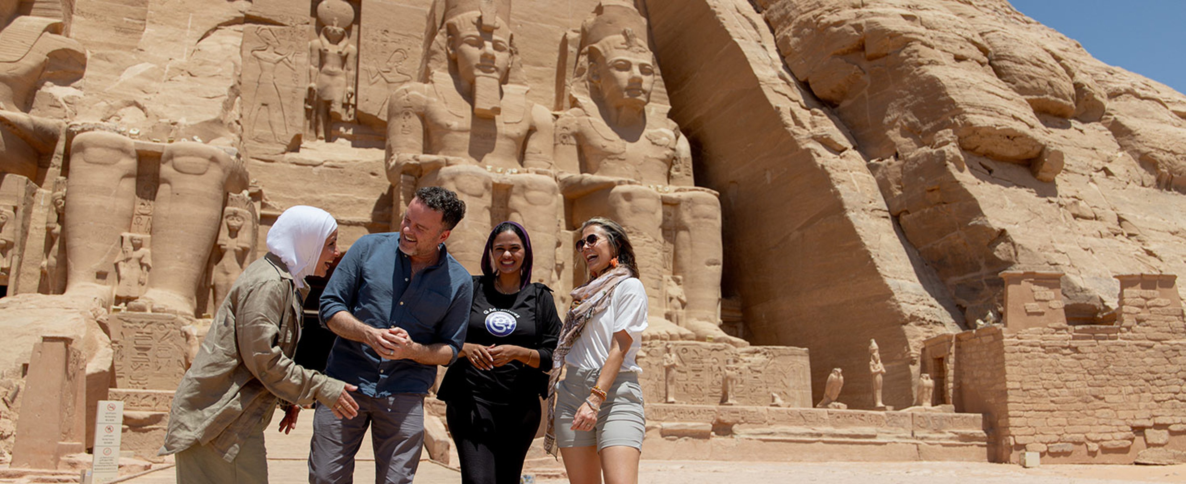 A group of four people in front of the colossal statues at the Abu Simbel temples in Egypt.