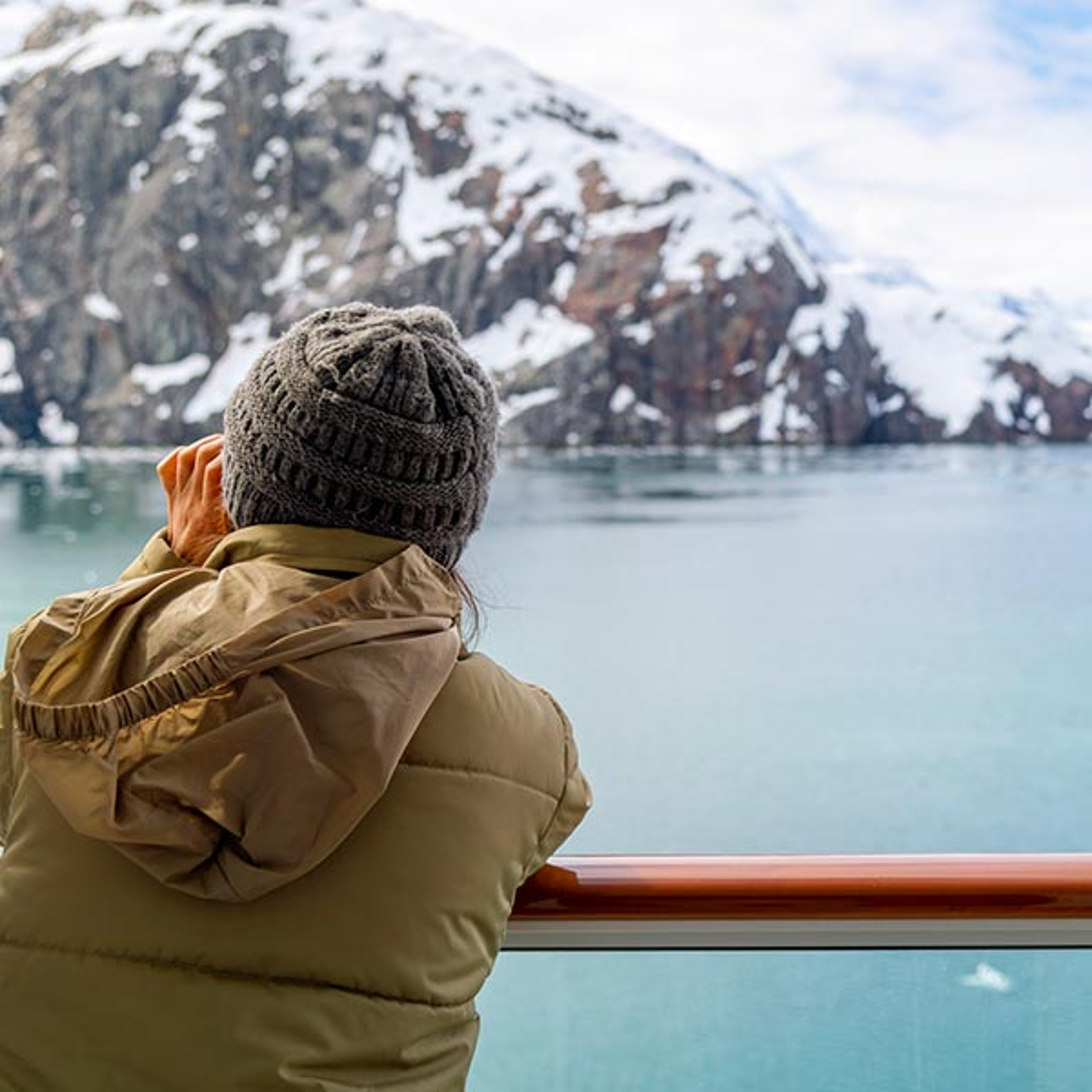 Cruiser on deck using binoculars to view Alaska wildlife and glaciers