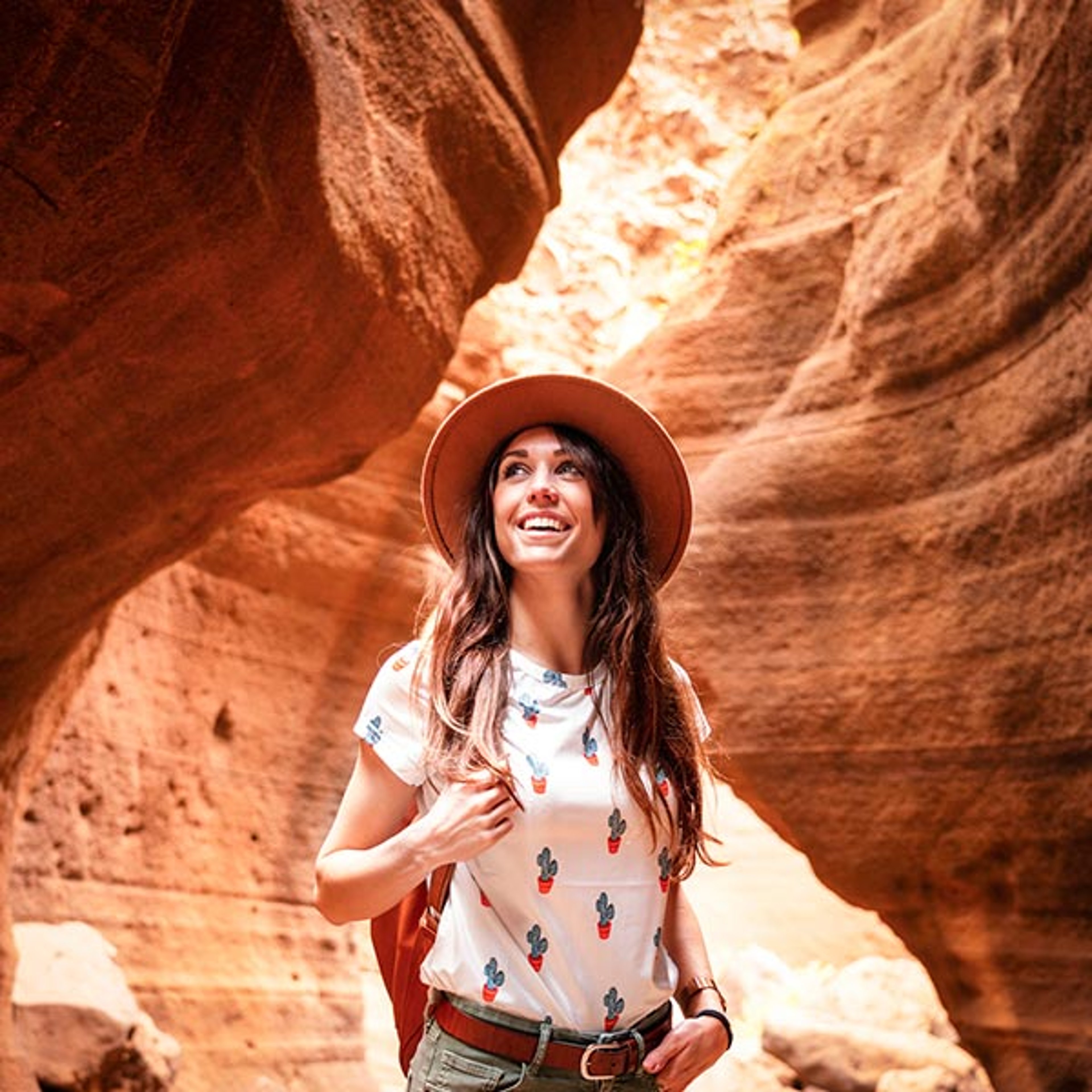 This image appears to show an individual exploring a scenic red rock slot canyon, which resembles locations like Peek-a-Boo Slot Canyon near Kanab, Utah