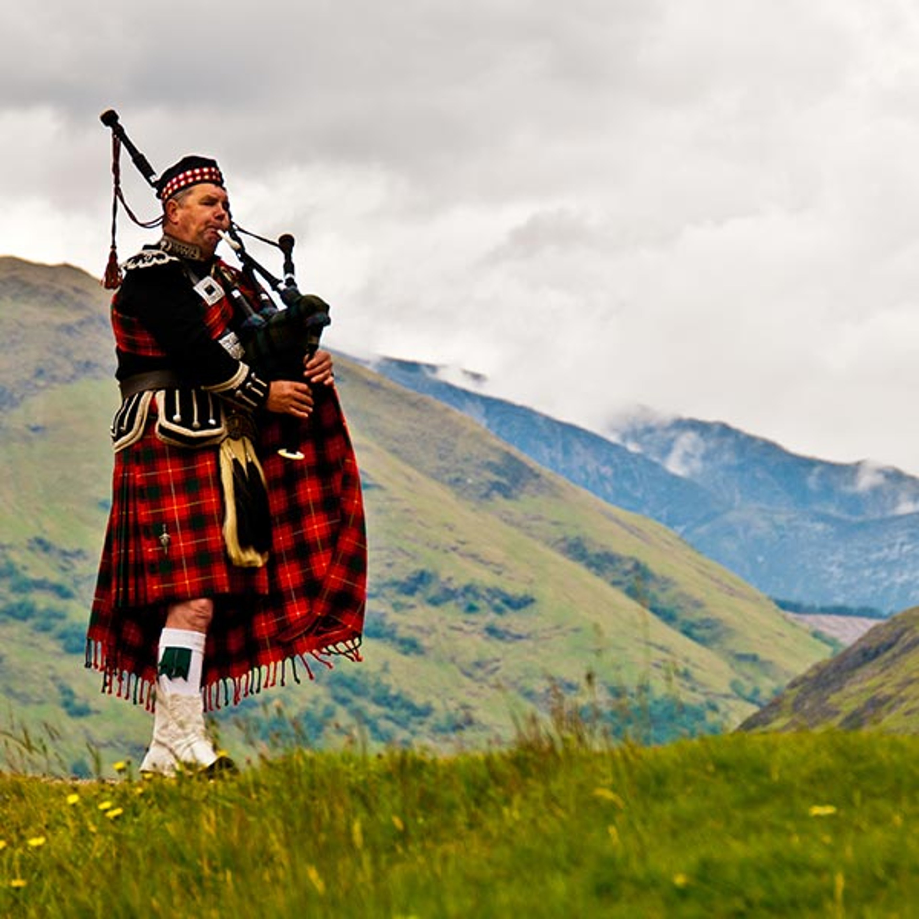 Bagpipe player standing in the Scotland countryside