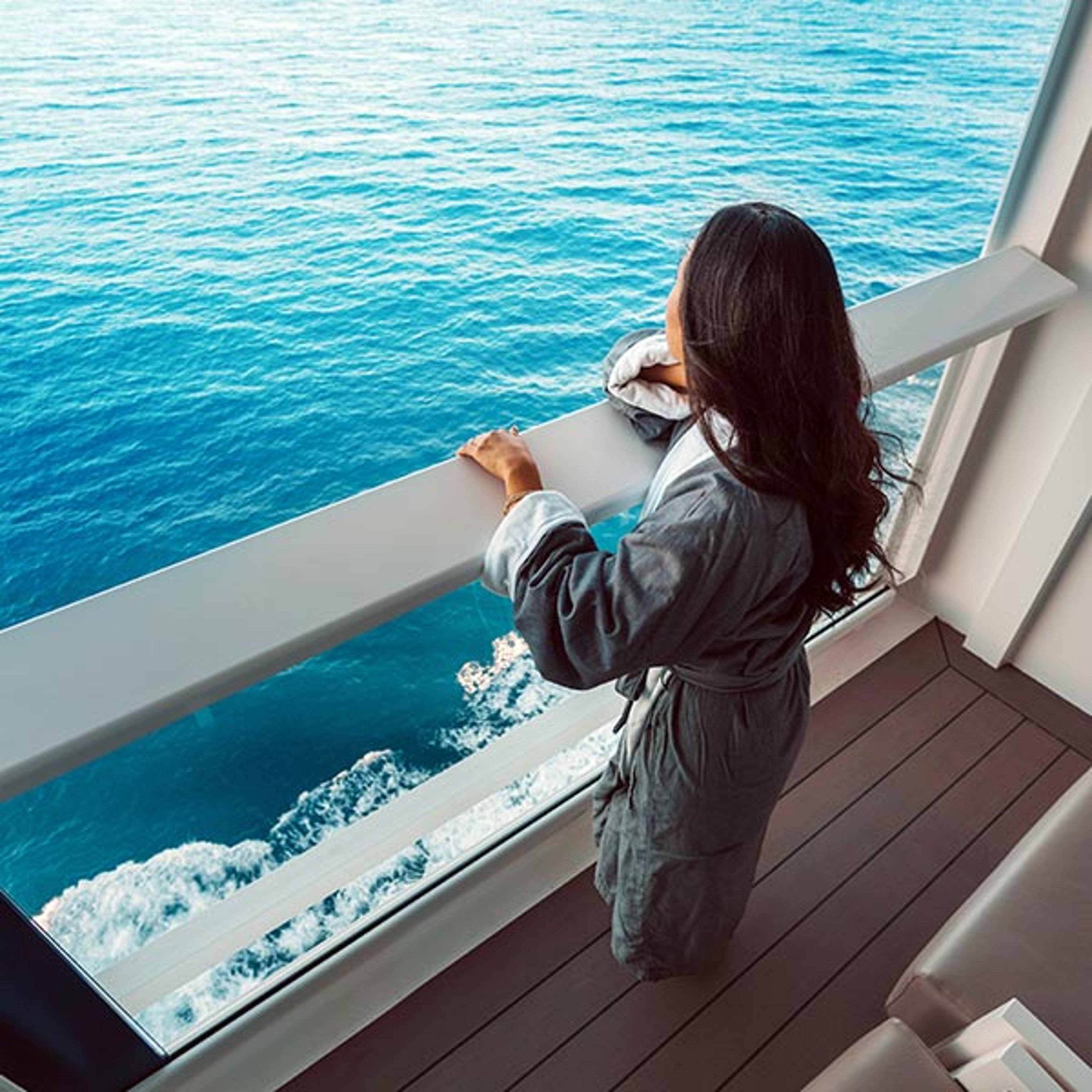Woman overlooking ocean while standing on her suite's verandah