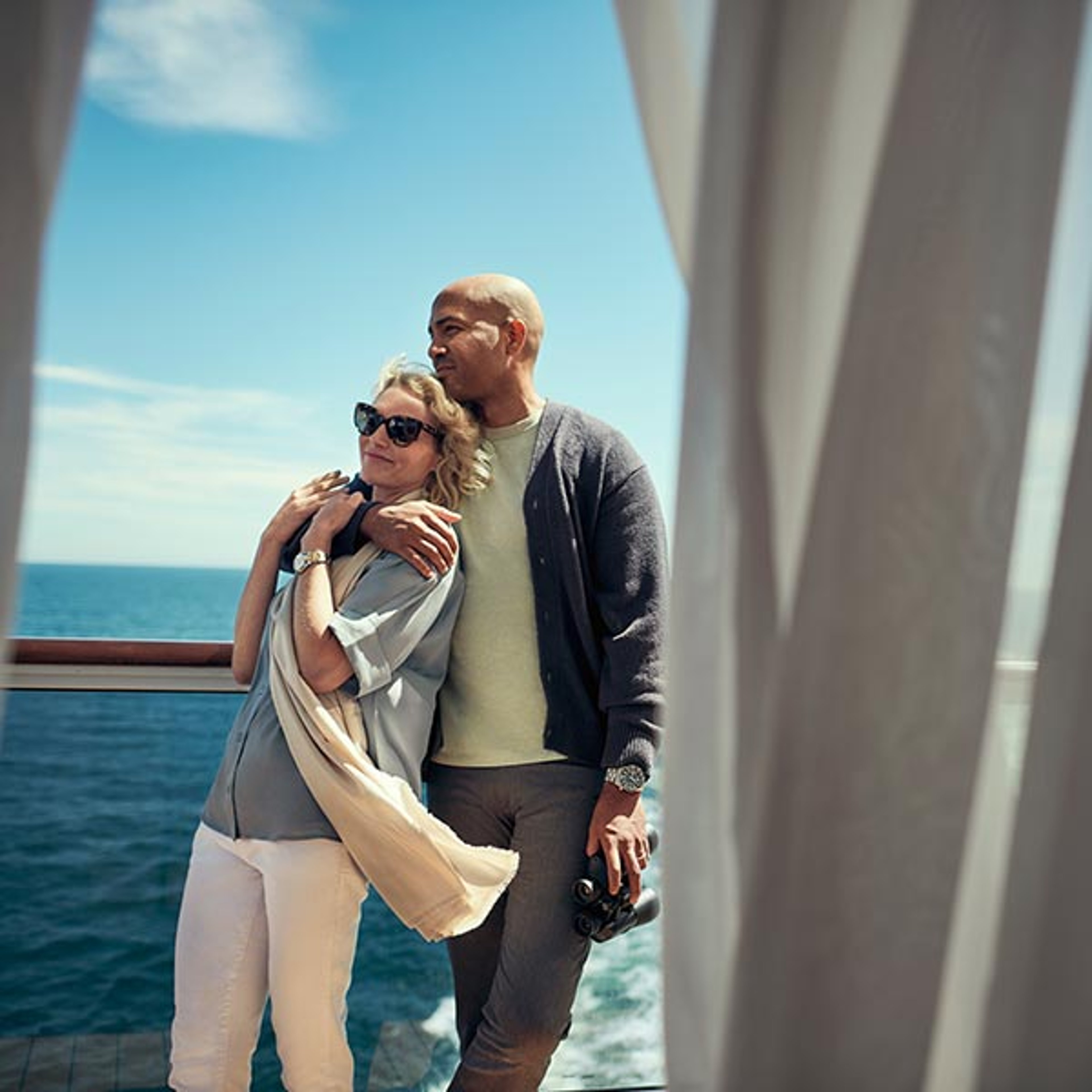 A couple enjoying their stateroom's balcony while cruising with Cunard in Alaska