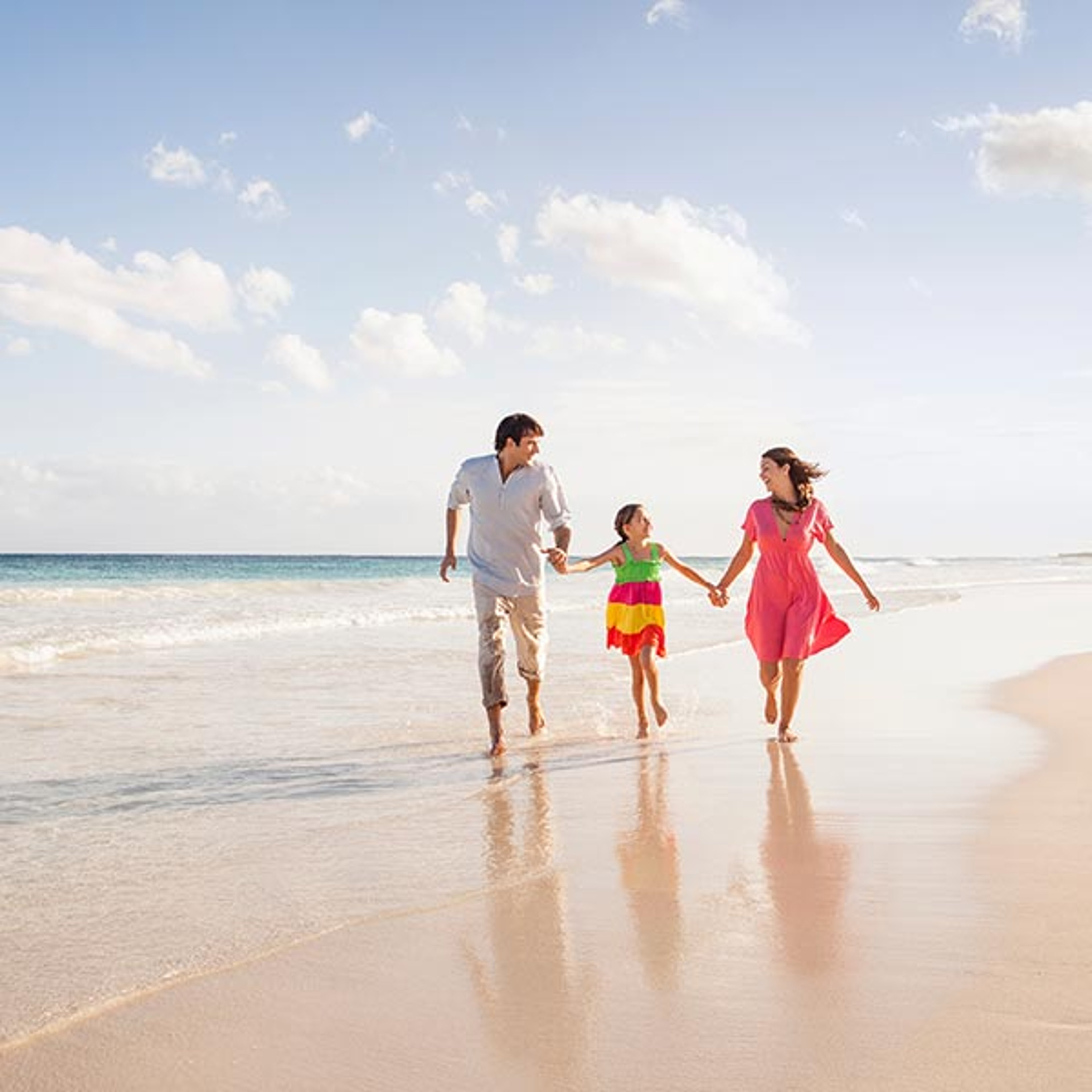 Mom, dad and daughter walking on a beautiful beach