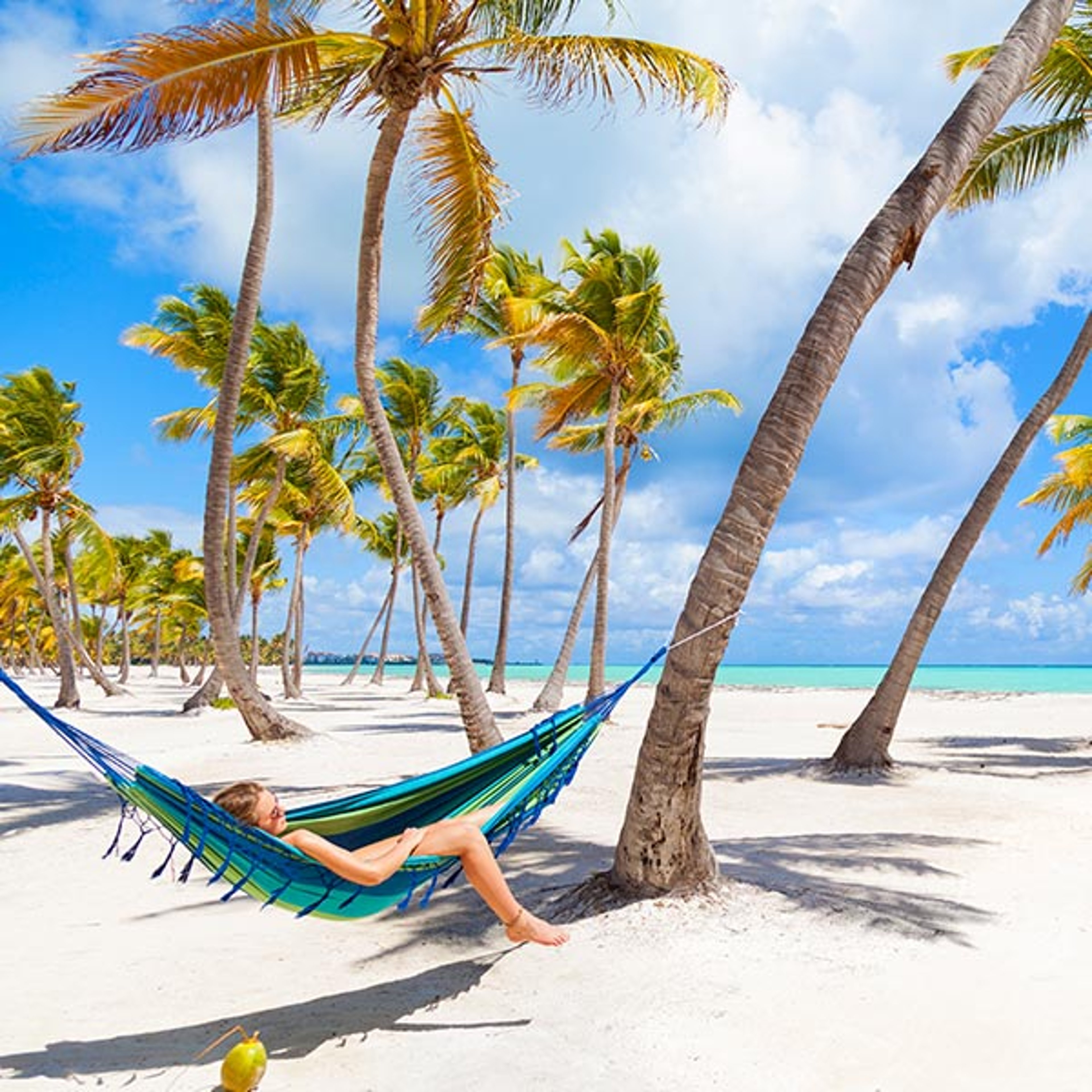 woman relaxing in a hammock on a beautiful palm tree lined beach