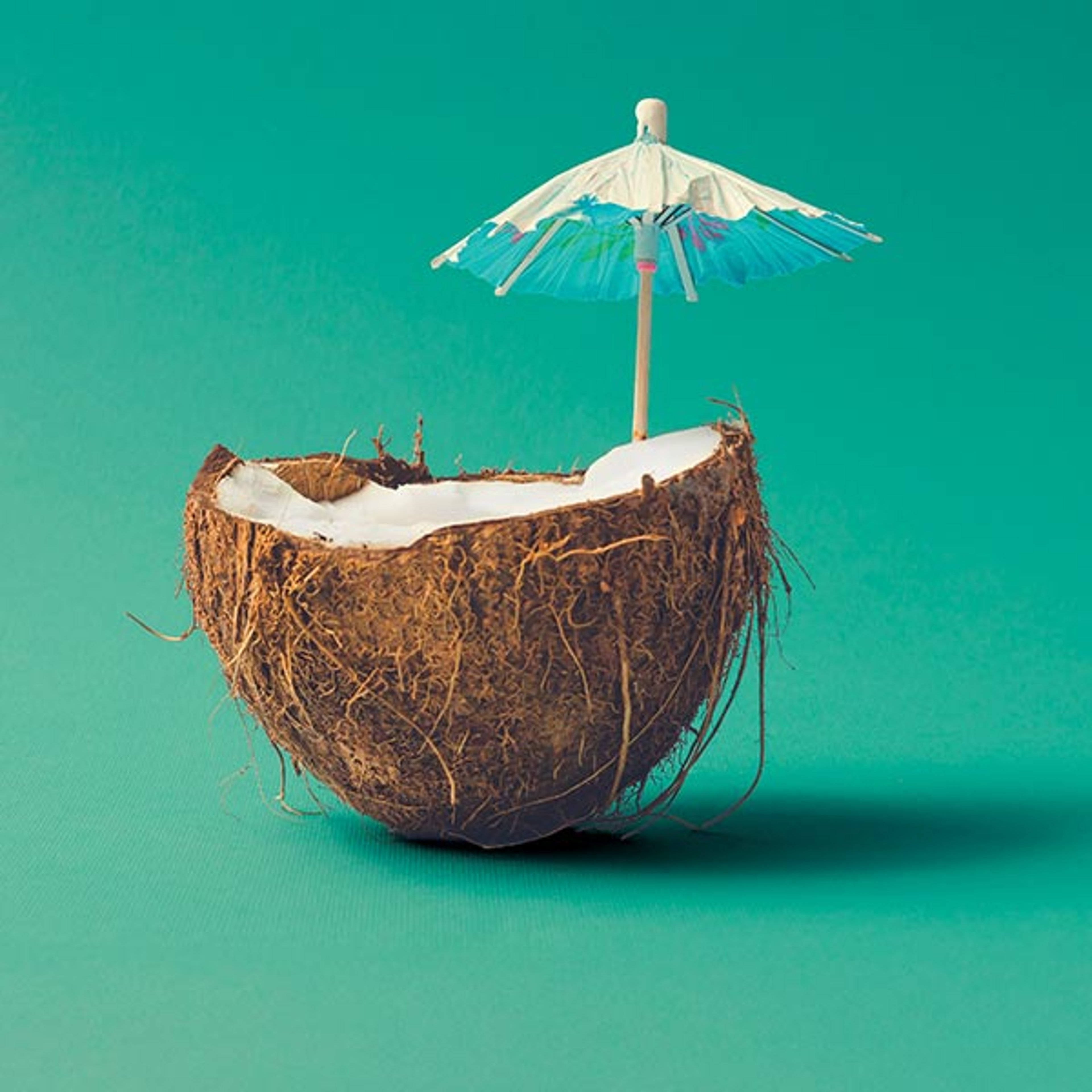 Coconut shell with drink and tiny umbrella