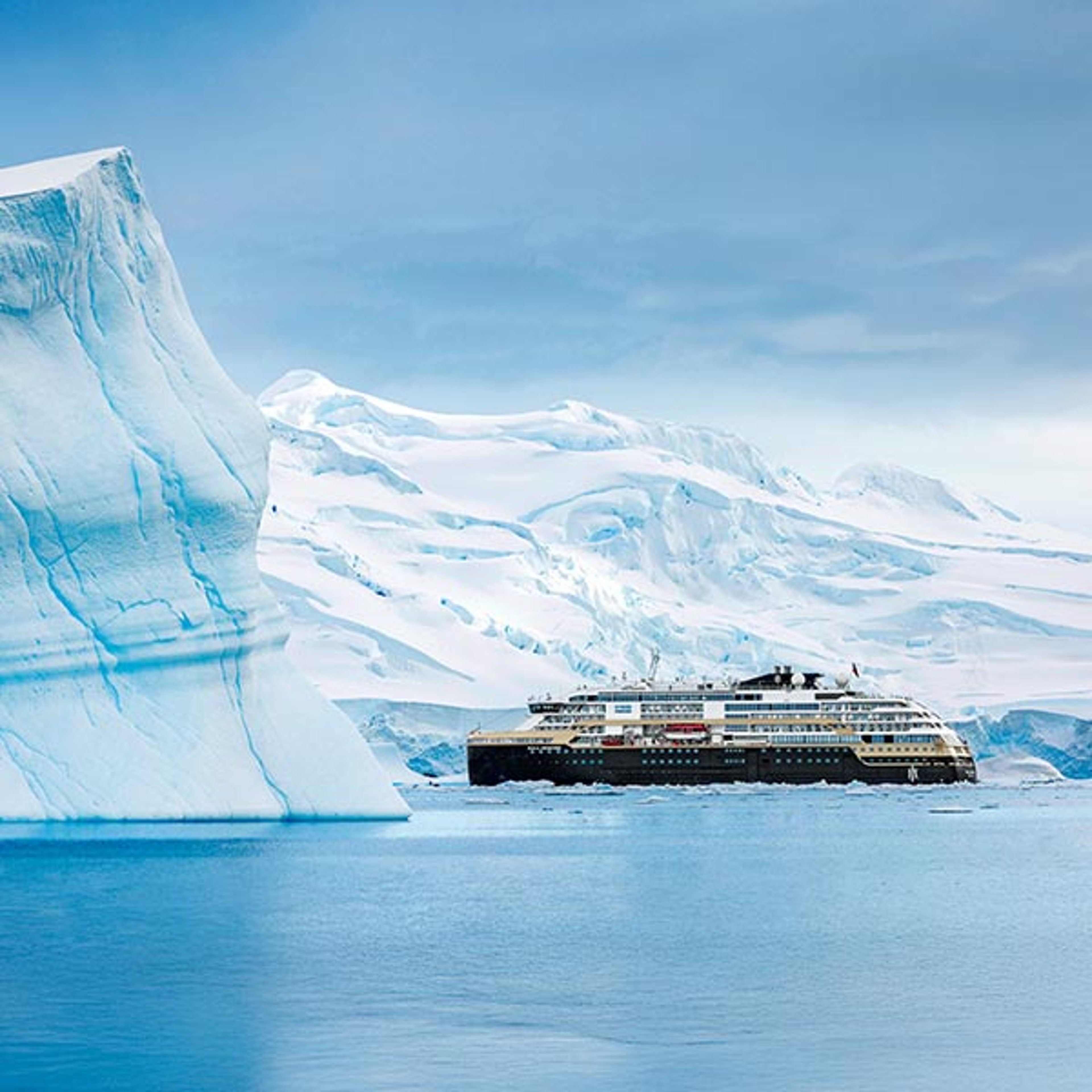 HX Expeditions ship cruising past an iceberg in Antarctica