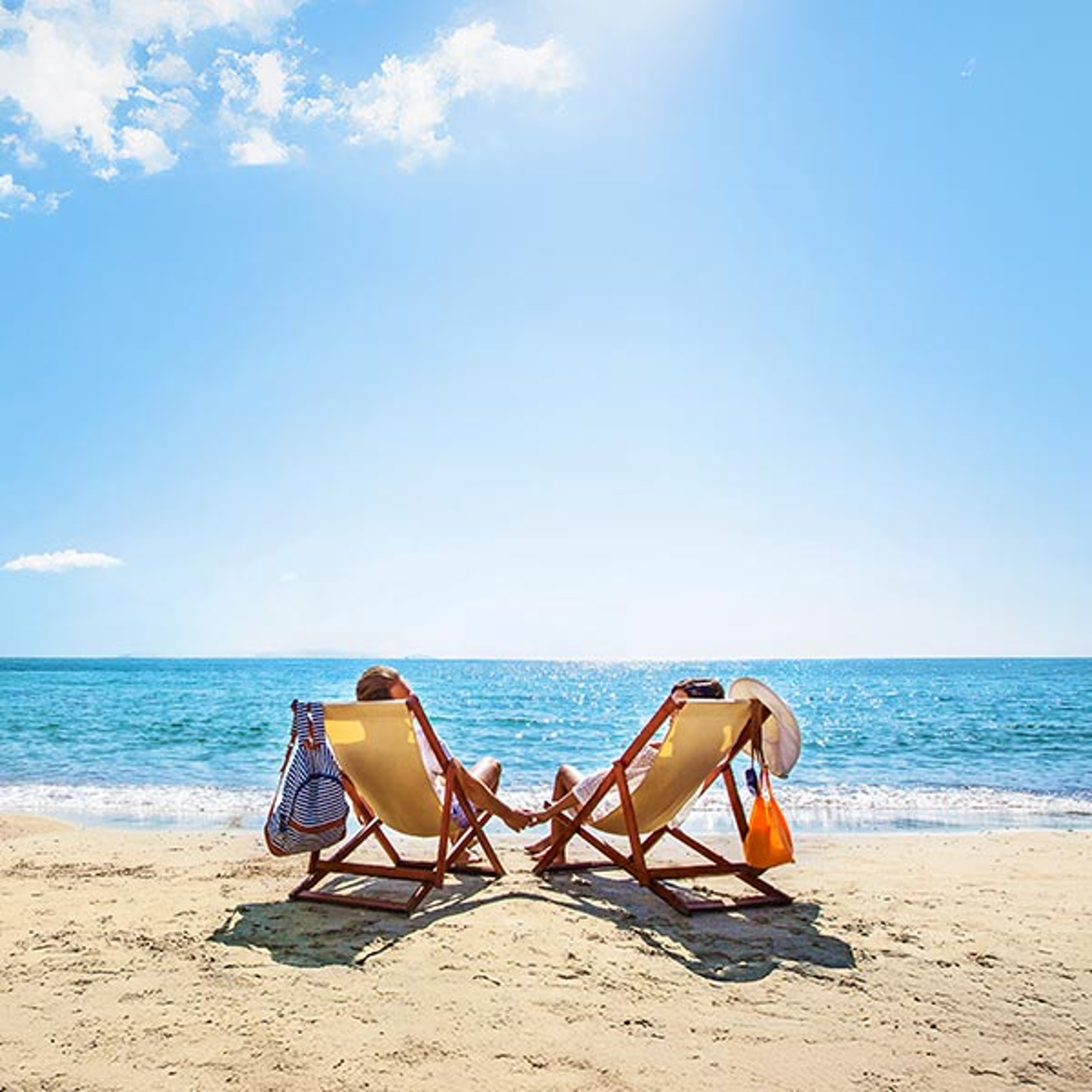 Couple in lounge chairs on a beautiful beach, relaxing while on a Holland america shore excursion
