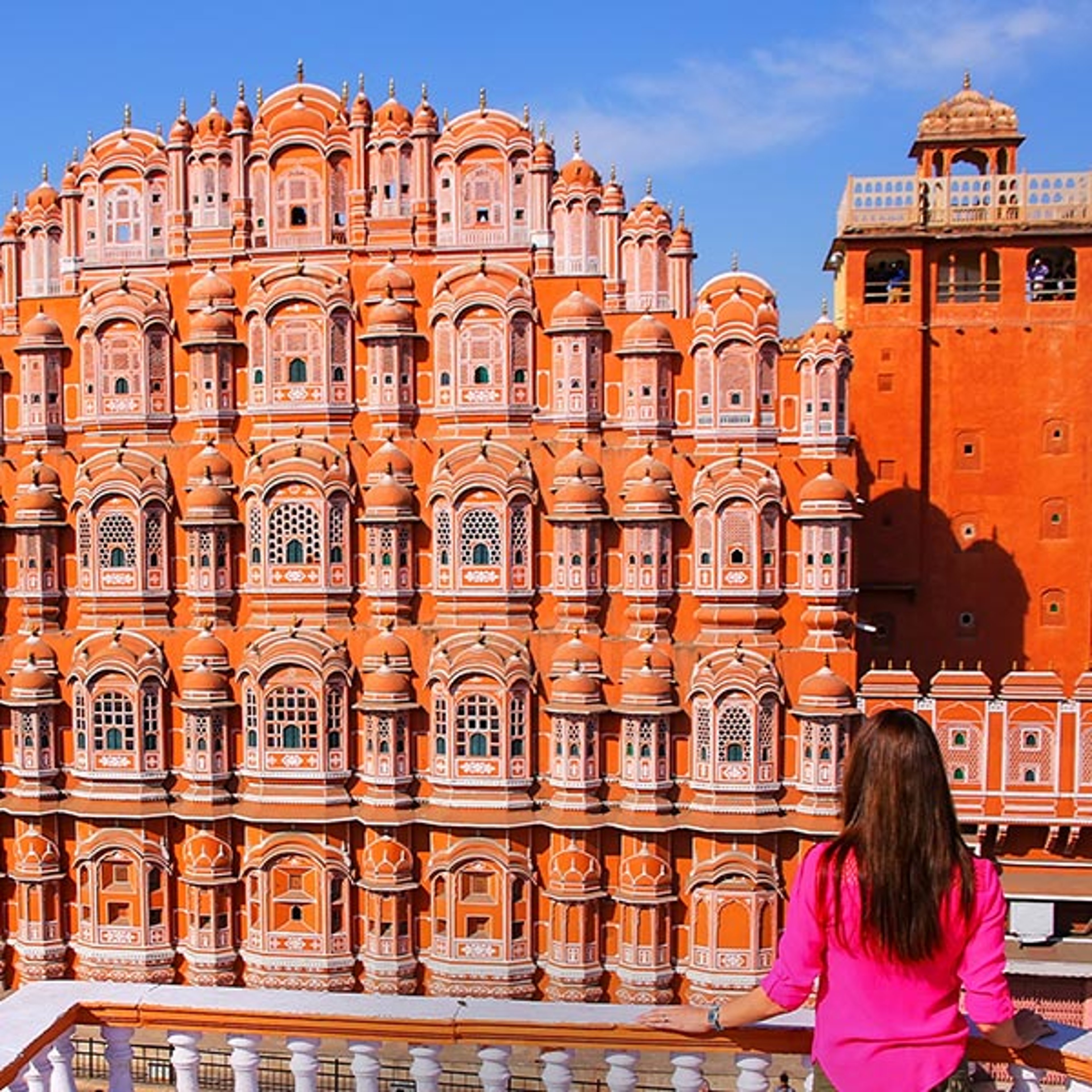 The image shows the ornate, five-story pink and red sandstone exterior of the Hawa Mahal in Jaipur, India.