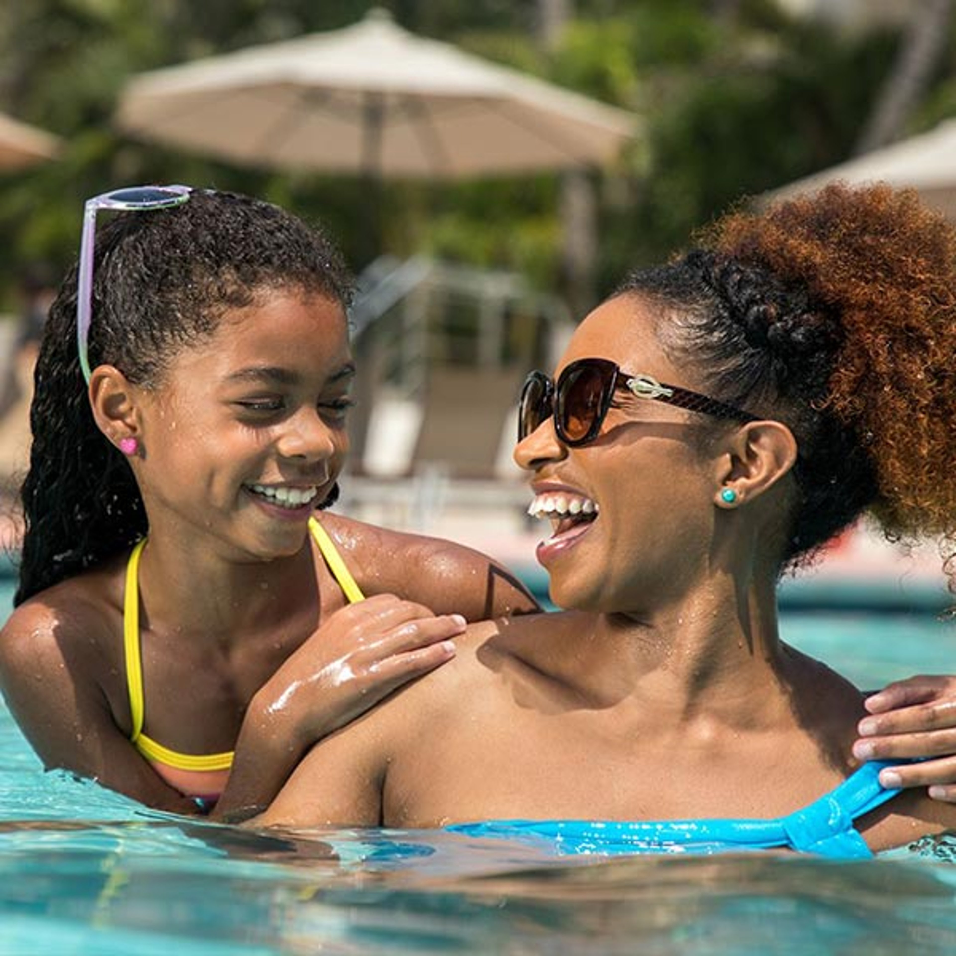 Mom and daughter laughing while enjoying the pool