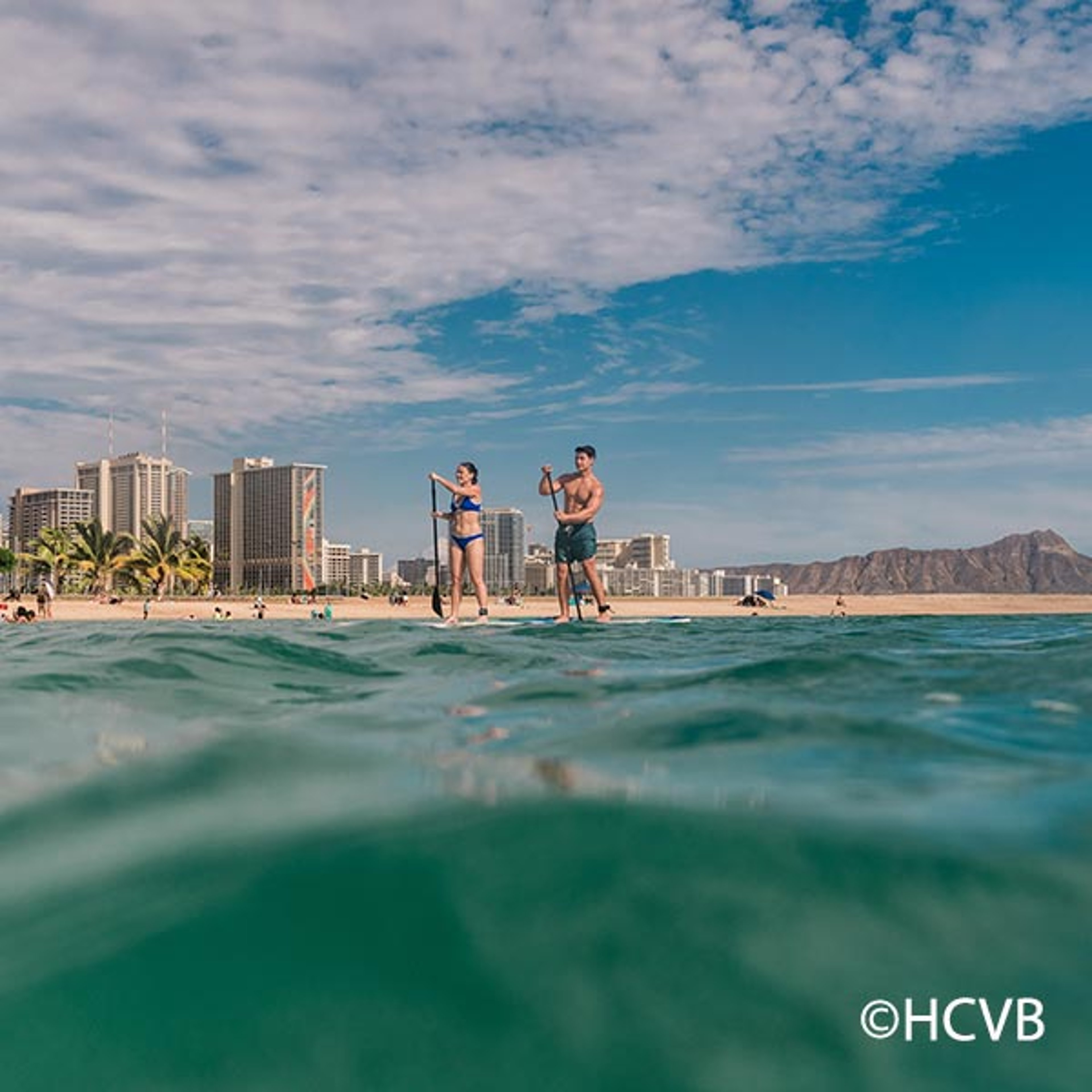 a couple paddleboarding through the waters in Hawaii