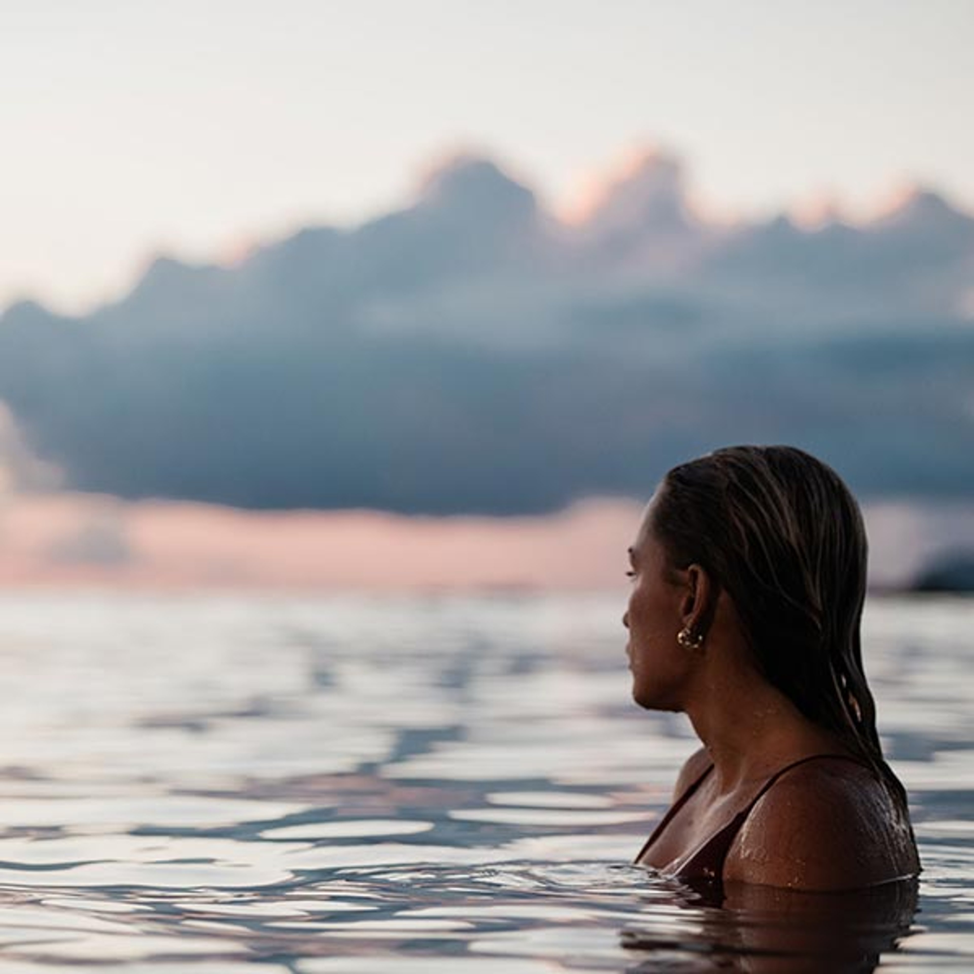 Woman in the ocean looking back toward Hawaii coastline