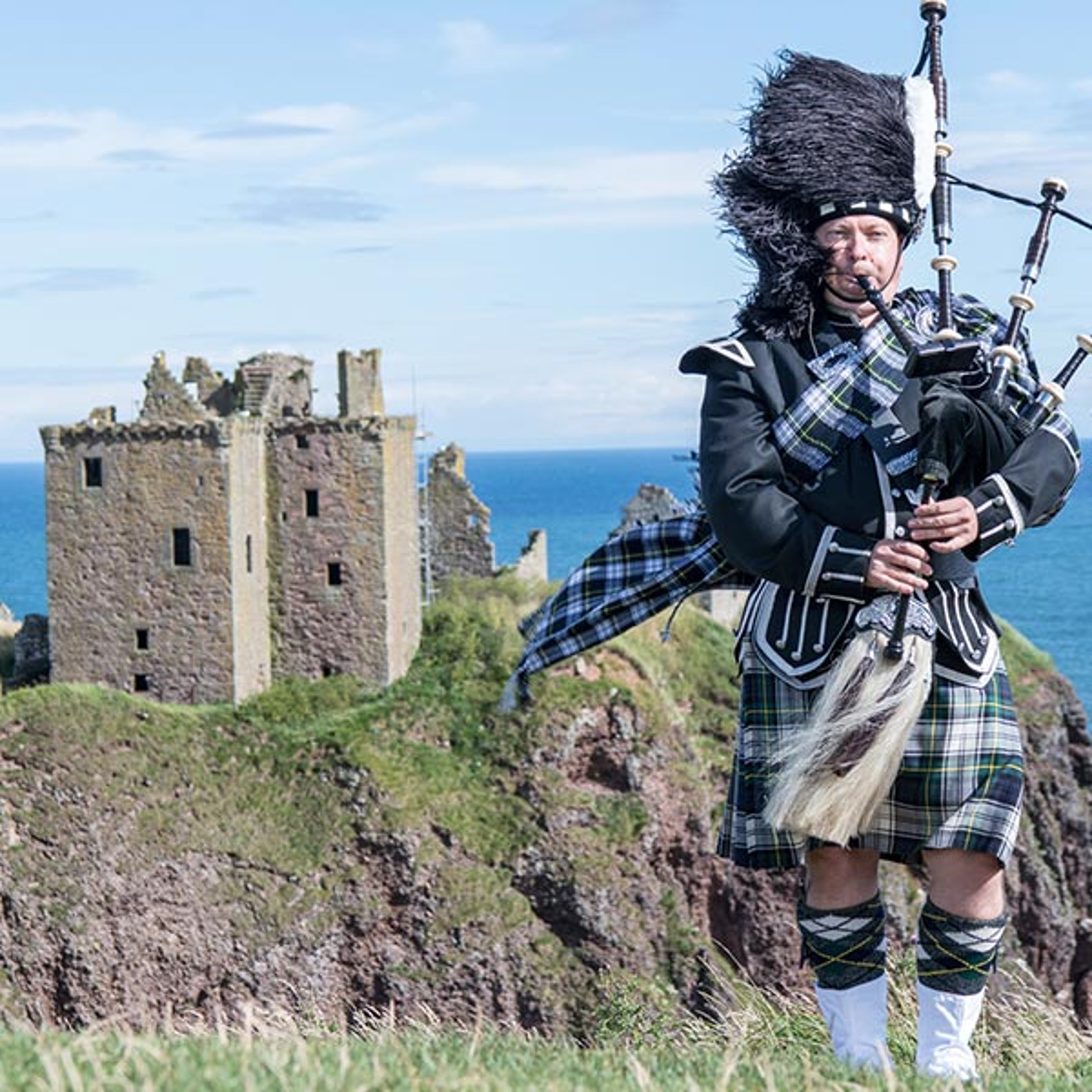 Bag piper near castle ruins in Scotland