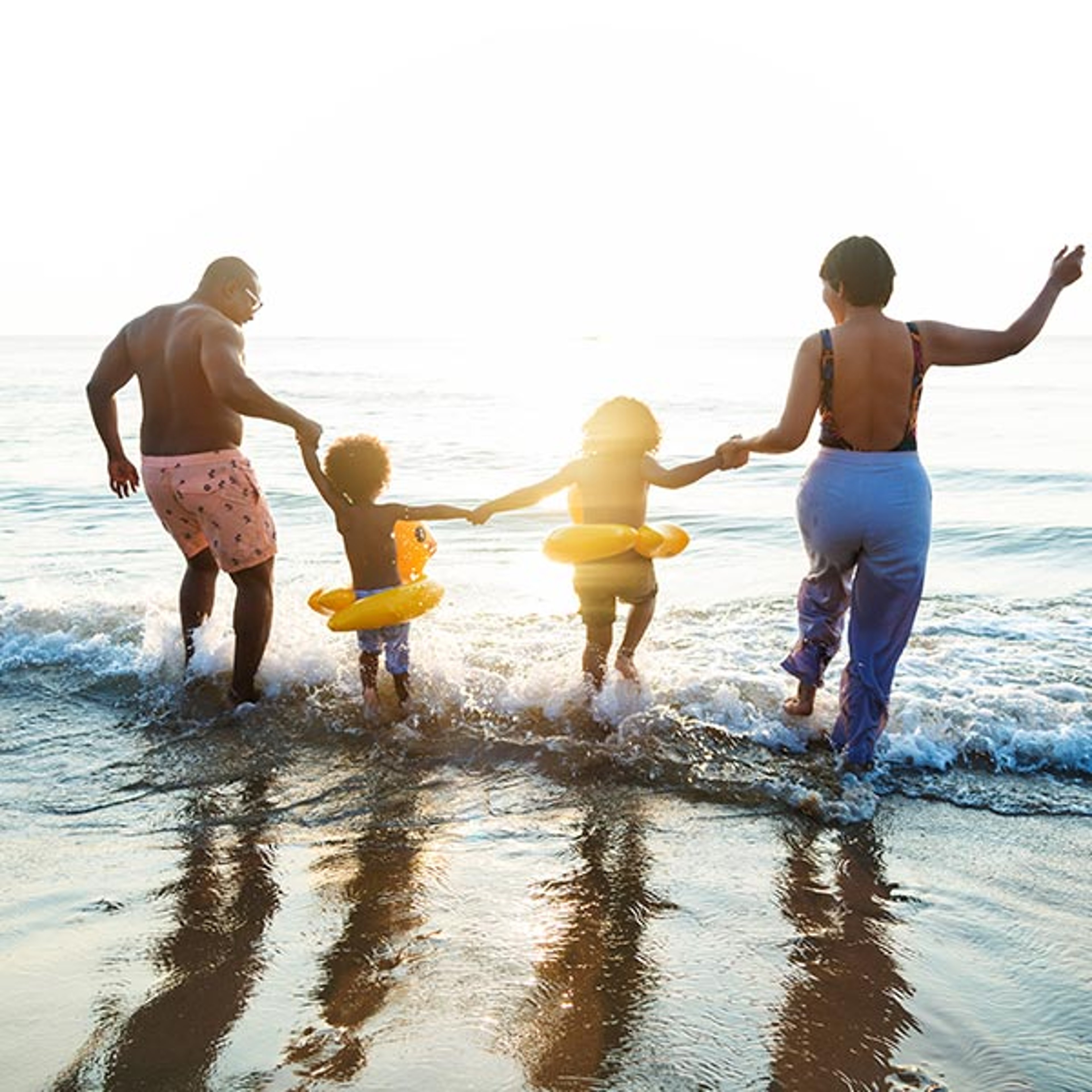 Family with two young children splashing in the water along the beach