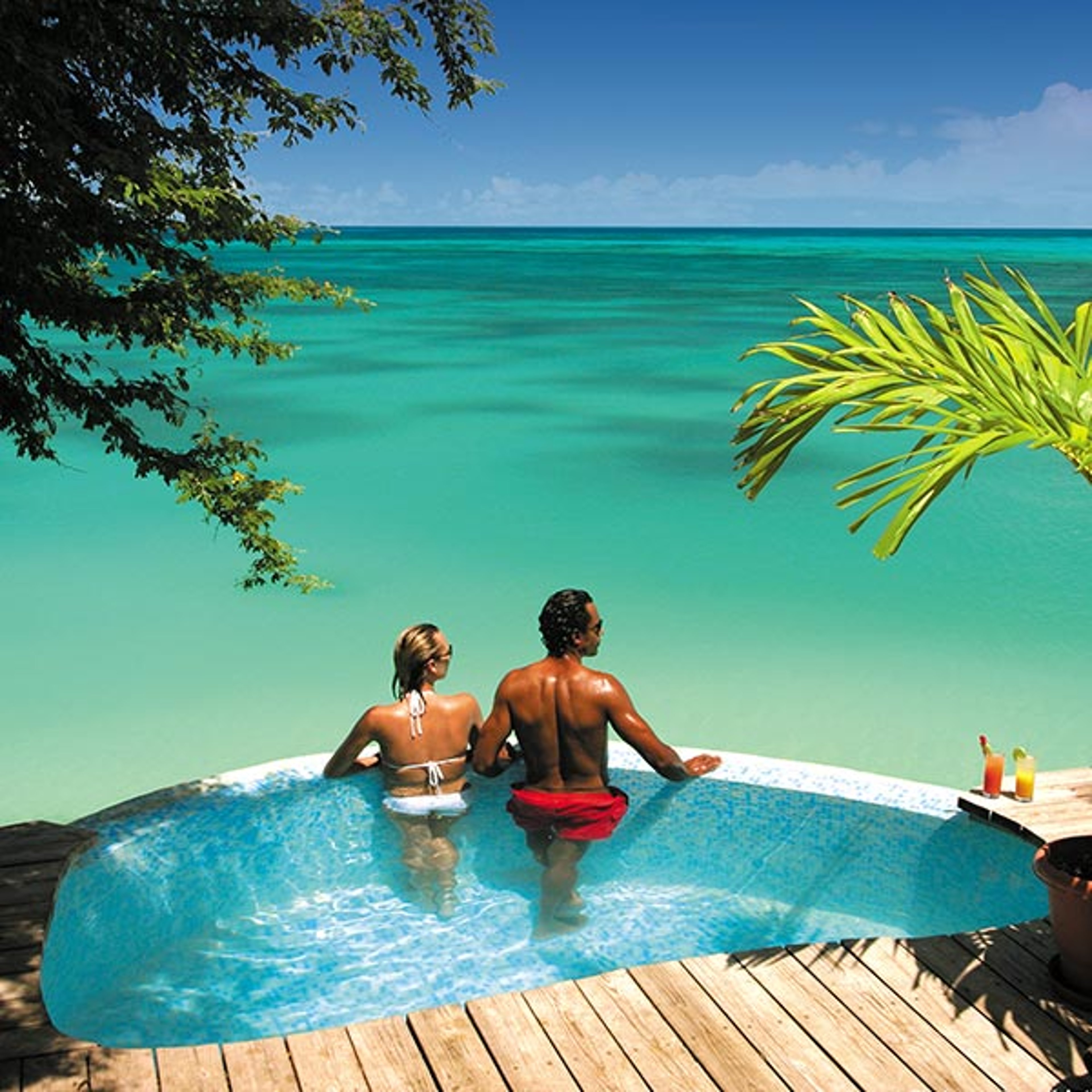 Couple standing in private pool overlooking the ocean