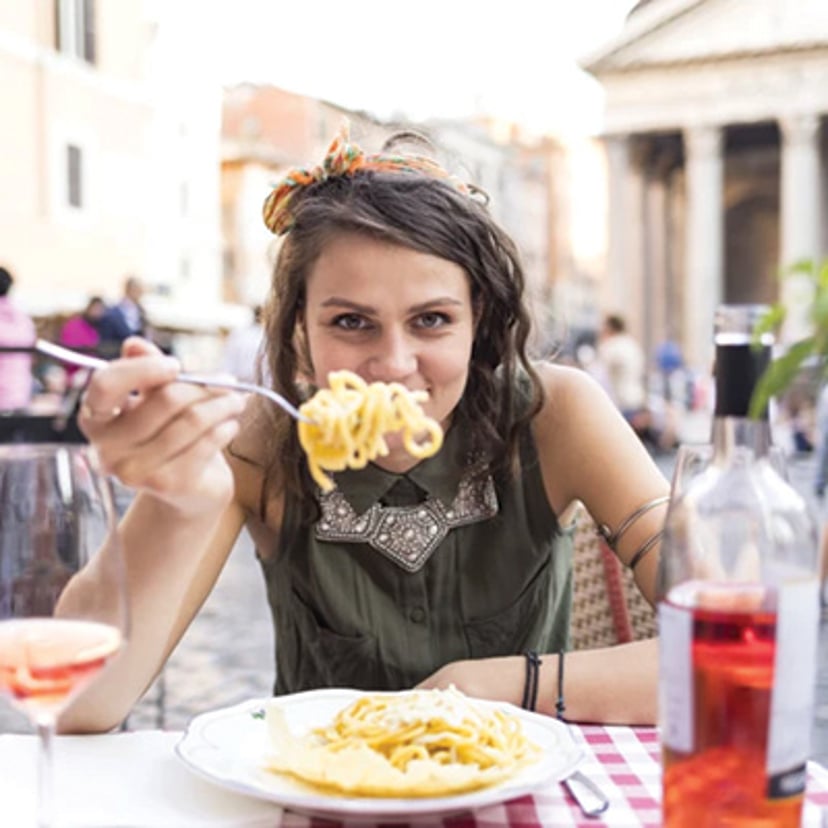 Woman eating pasta at an outdoor café in Rome.