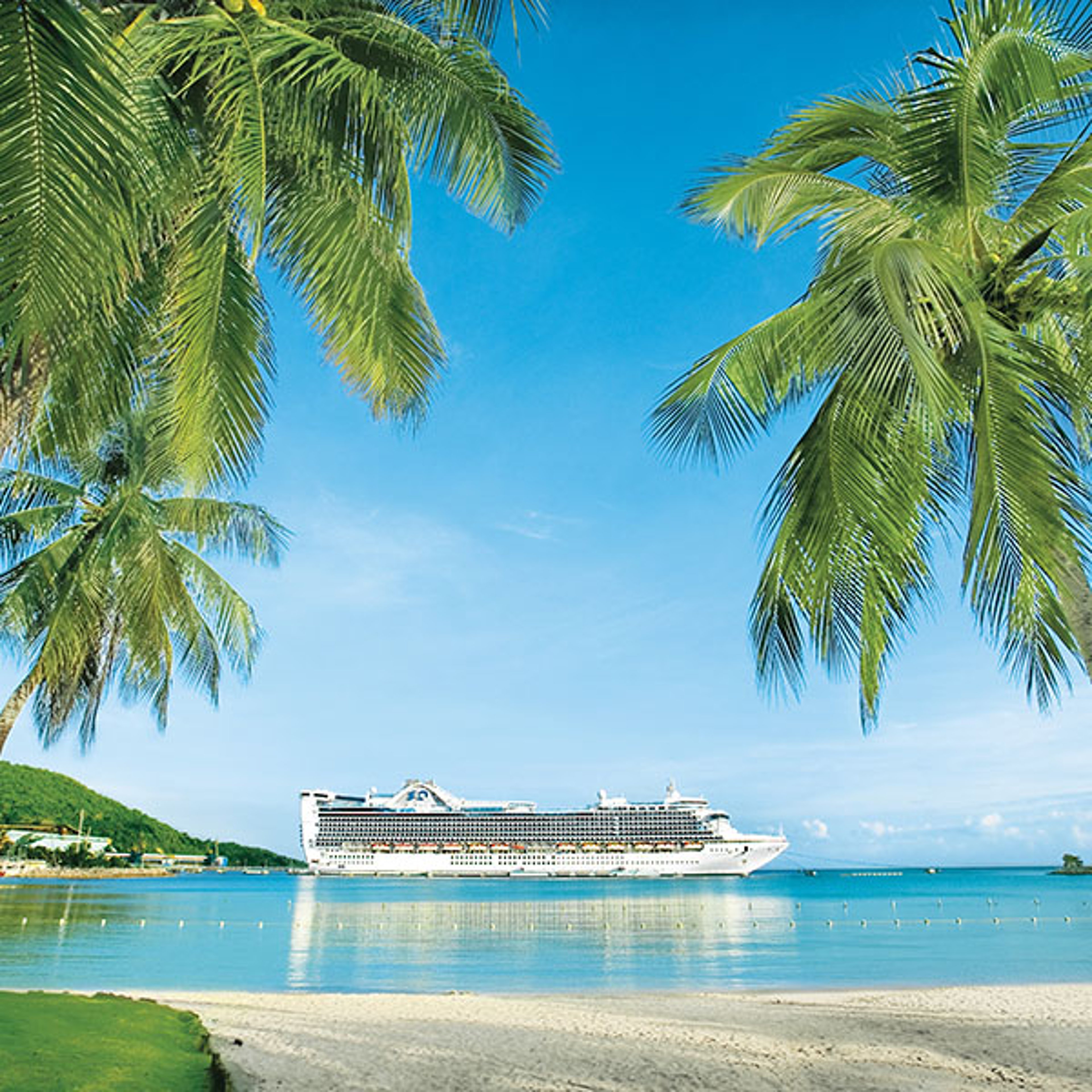Cruise ship anchored near the shore, framed by palm trees, in Ocho Rios, Jamaica.