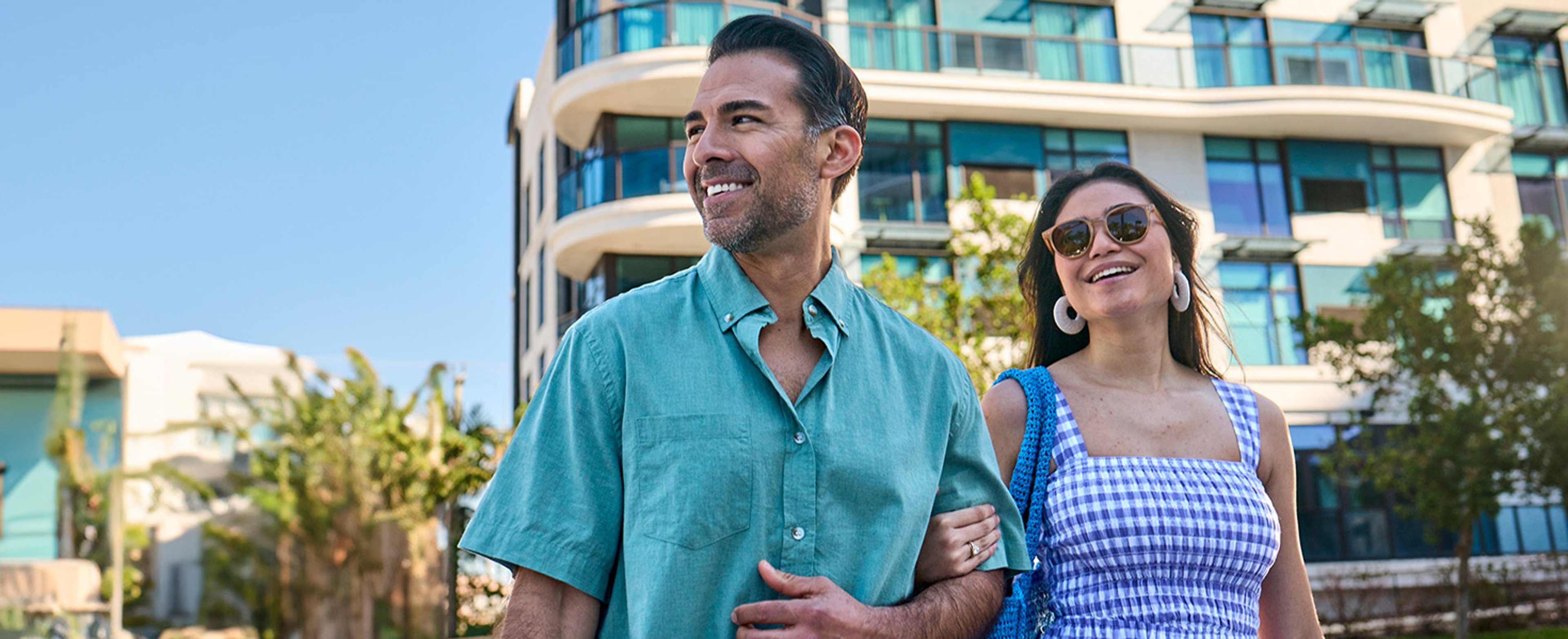 Smiling couple walking arm in arm in front of a Choice Hotel property