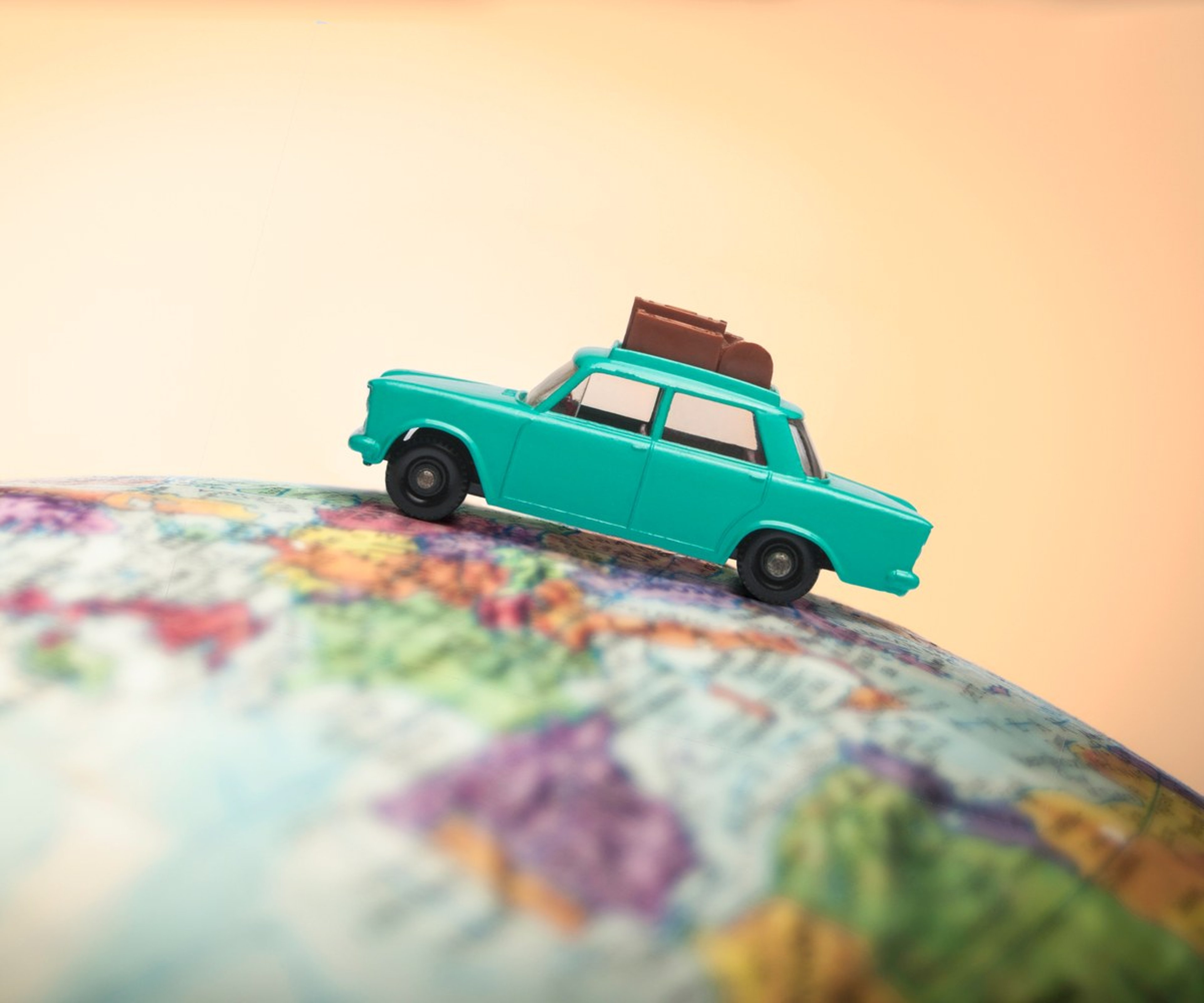 Model car with luggage on a globe for international travel