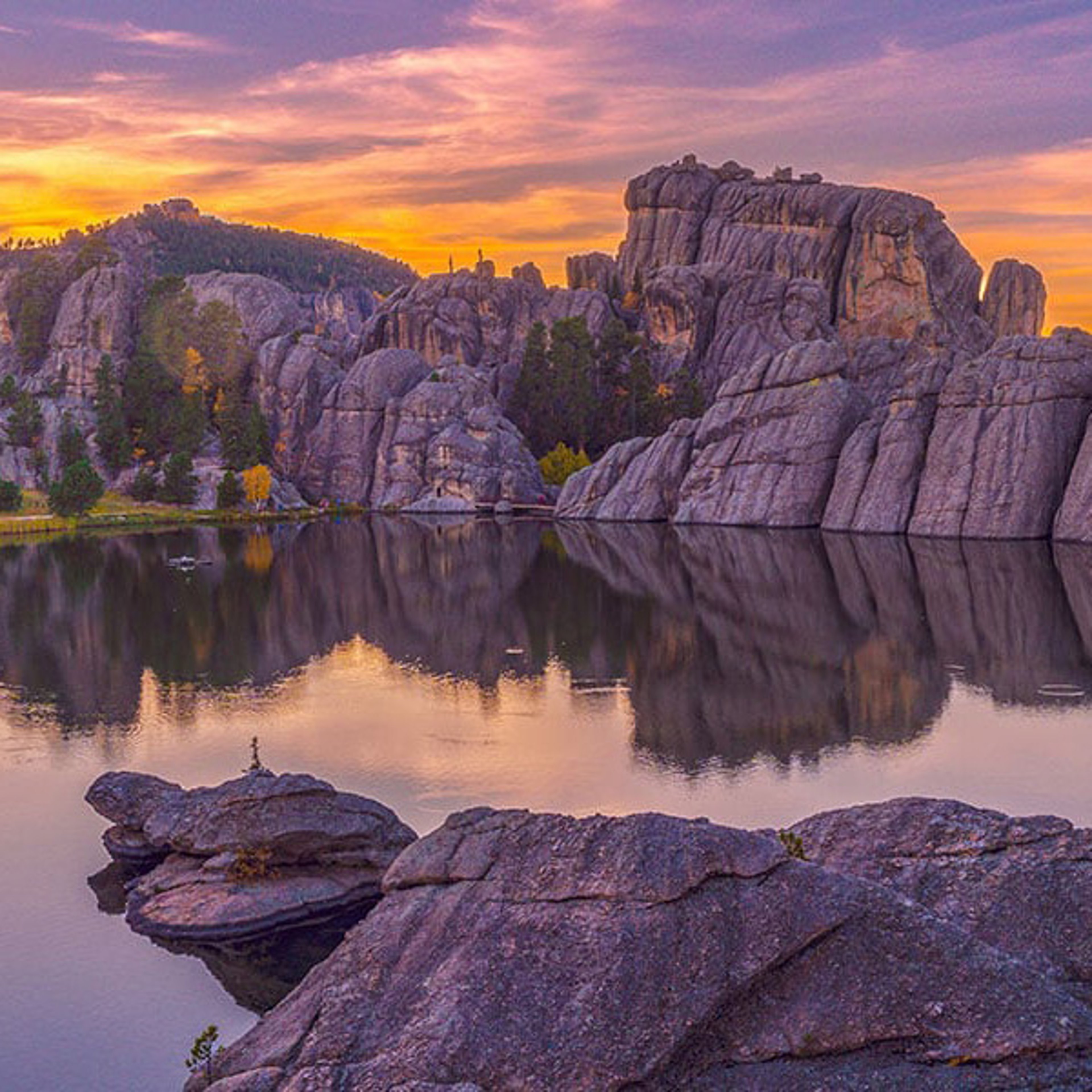 Sylvan Lake in Black Hills during a vivid sunset with rock formations and reflections in the water