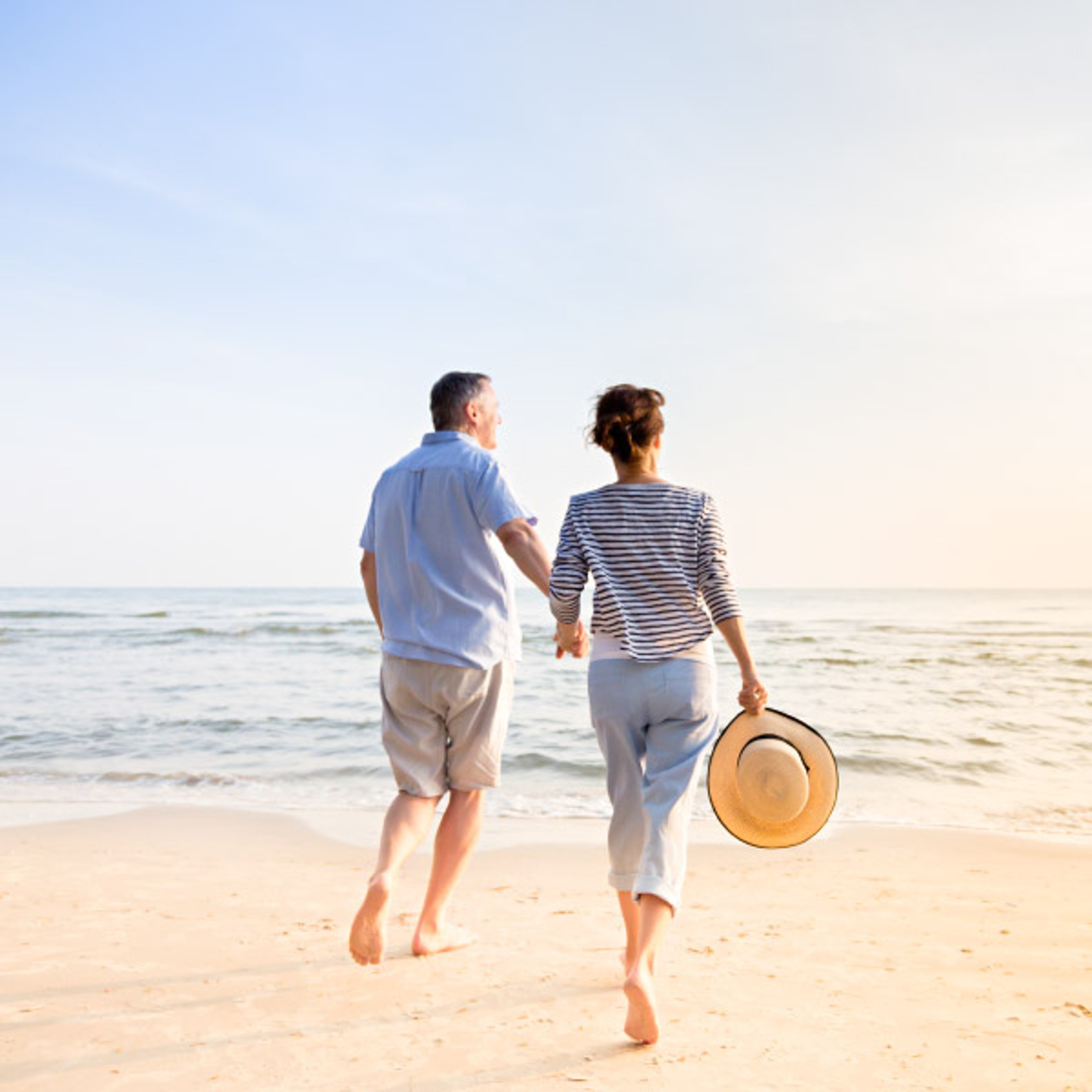 Couple strolling down the beach alongside the ocean