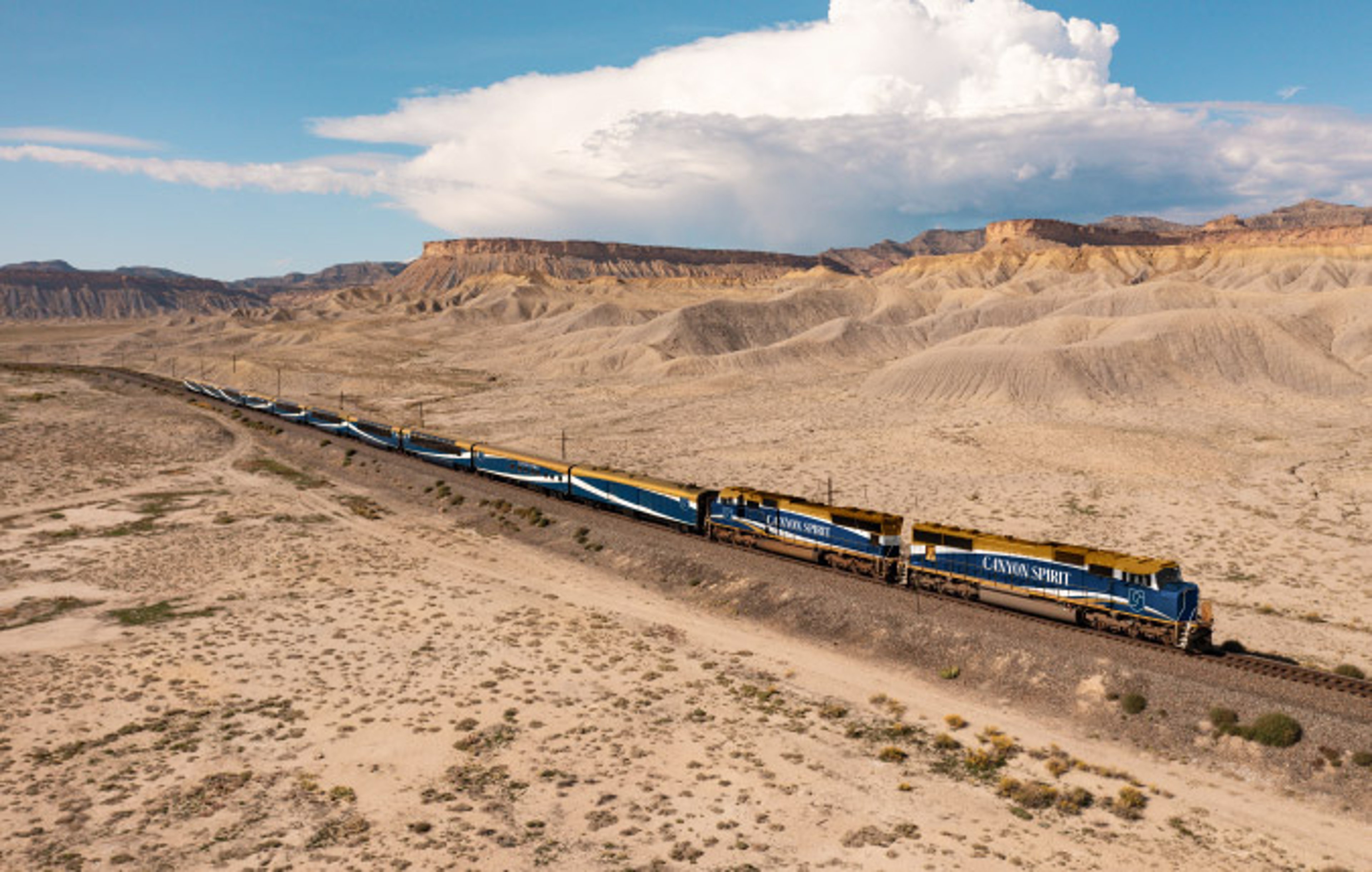 Canyon Spirit luxury train traveling through the sand dune scenery of Seven Mile Canyon in Colorado.