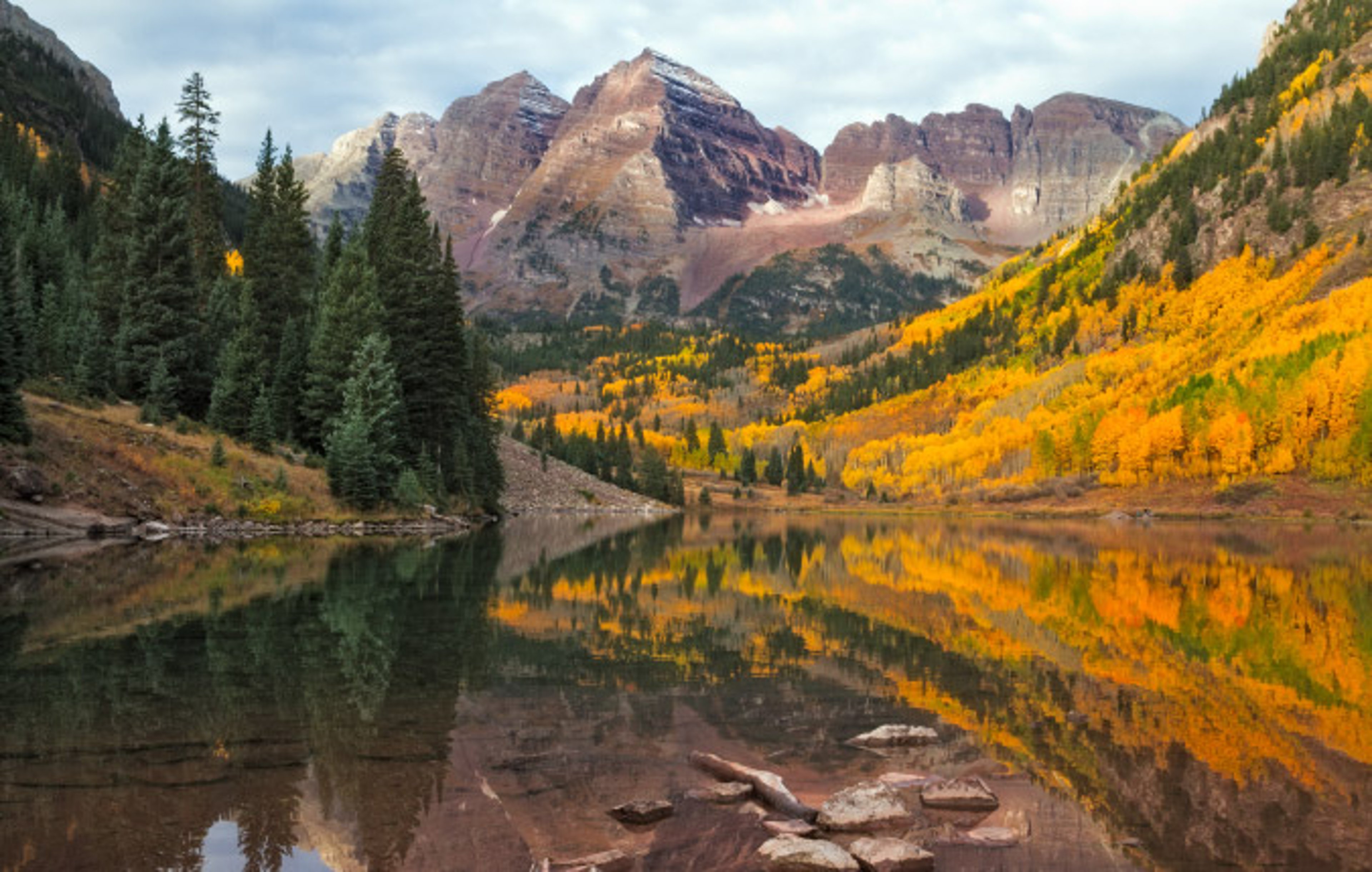 Morning sunrise over Maroon Bells peaks in Colorado with lots of trees and fall colors
