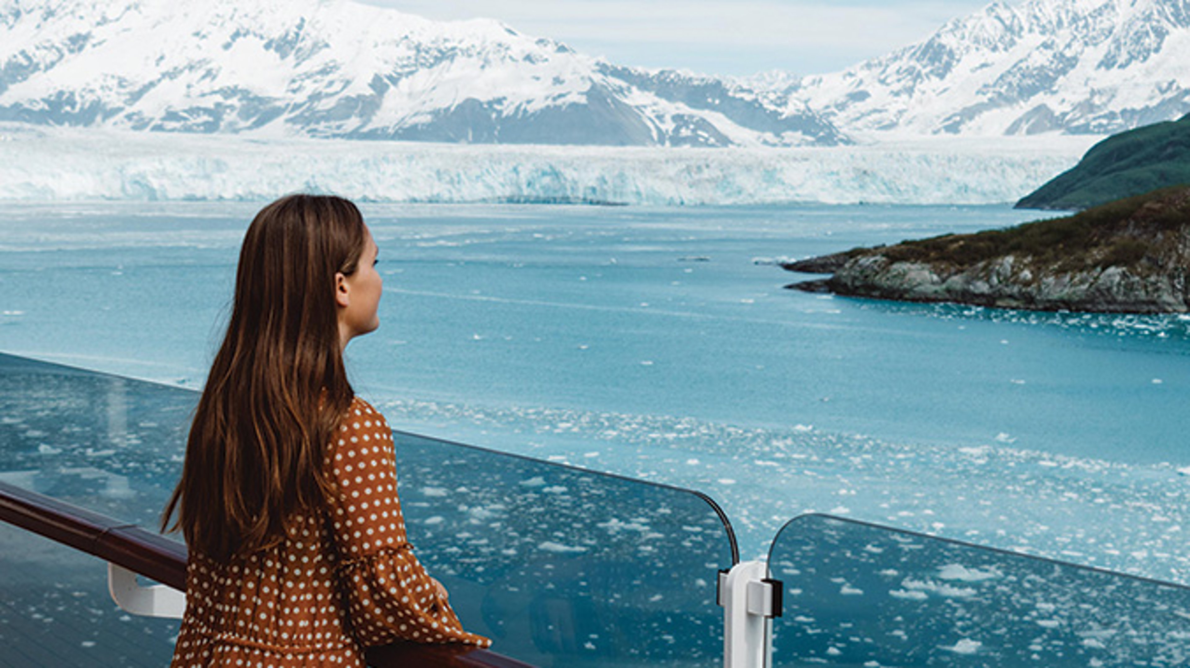 AAA Travel Set Sail Cunard Woman overlooking deck of Cunard Queen Elizabeth ship with view of Alaska glacier