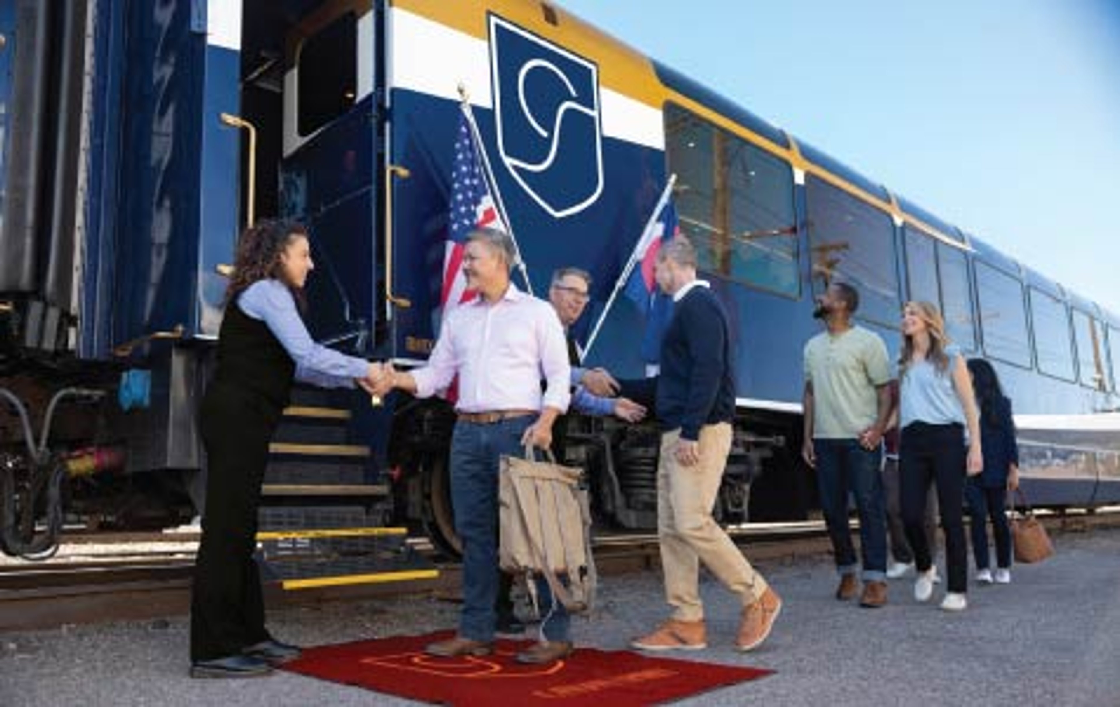 Travelers boarding a luxury Canyon Spirit train, greeted by staff on a red carpet at the station platform.