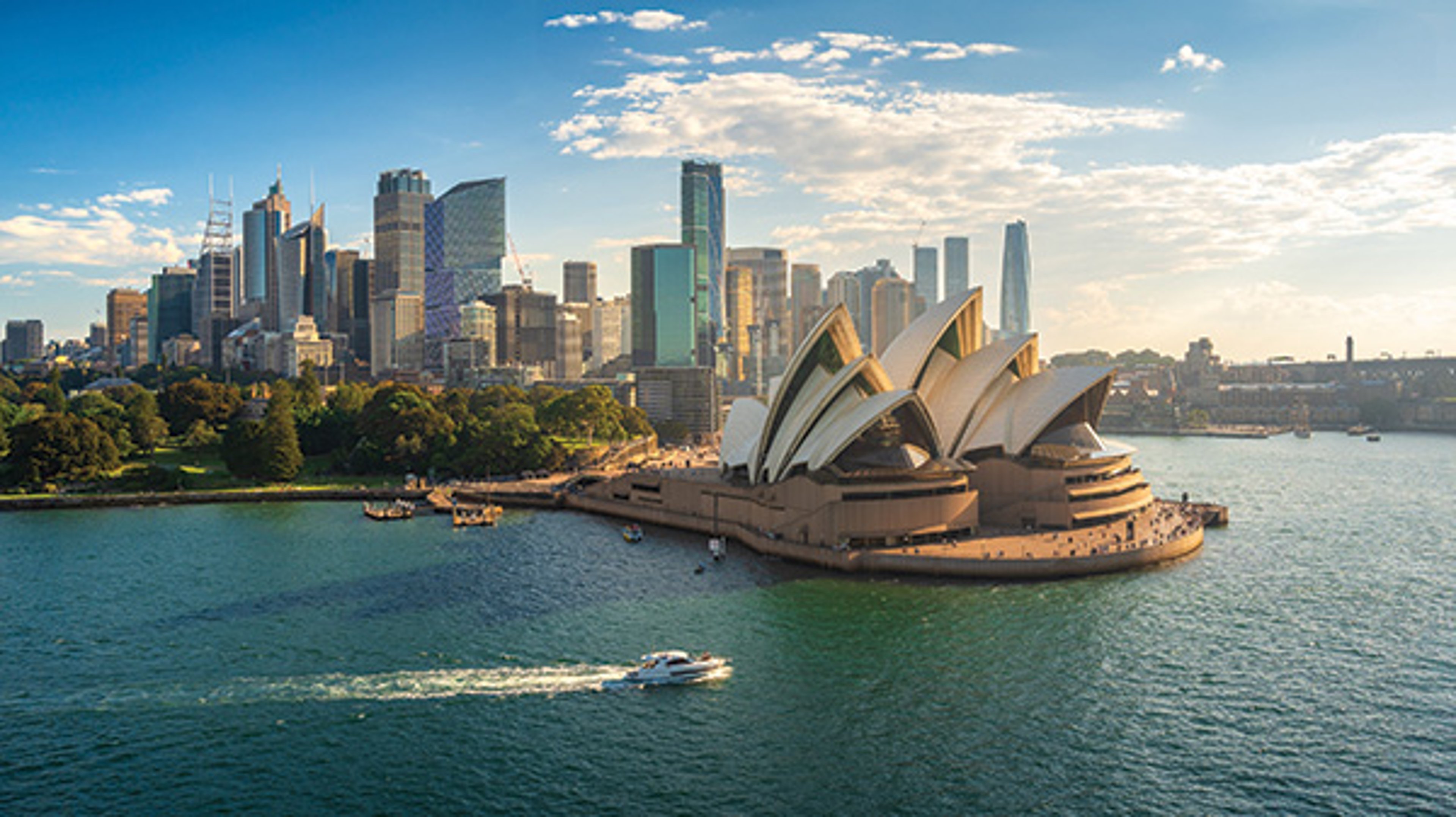 Sydney Opera House with city skyline in the background over Sydney Harbour.