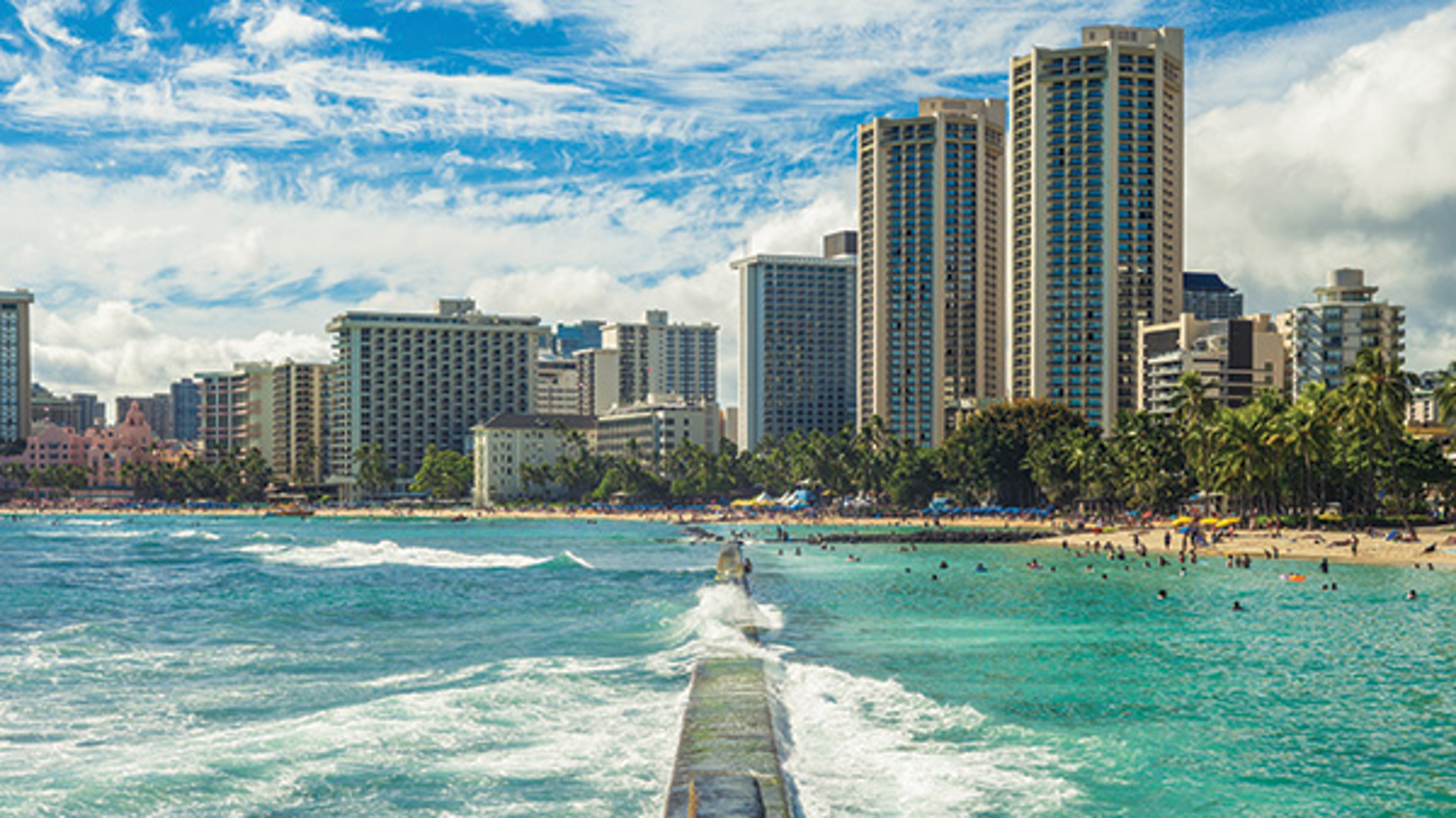 Waikiki Beach with high-rise hotels, turquoise ocean, and a lively beach scene.