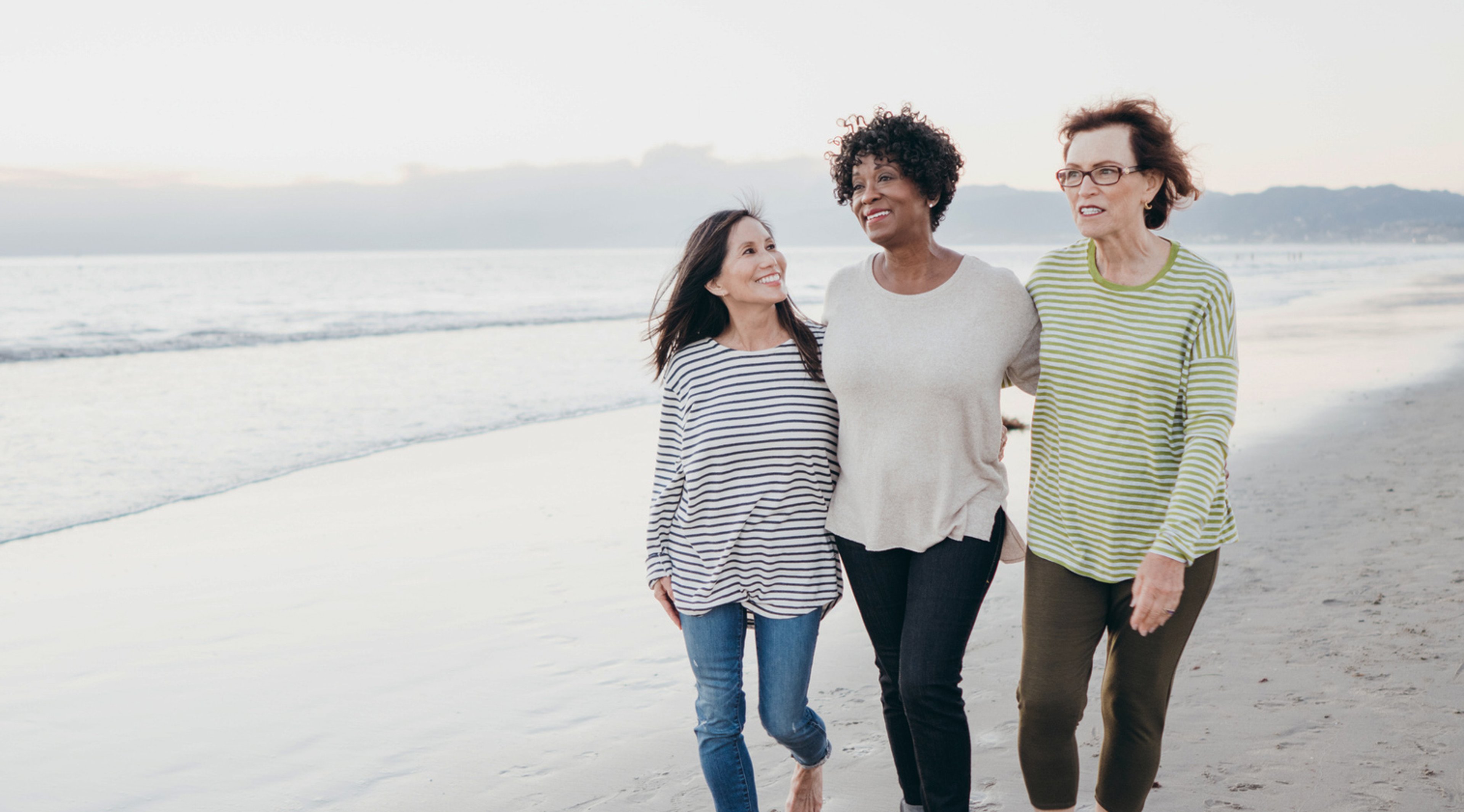 Three older women walking on the beach