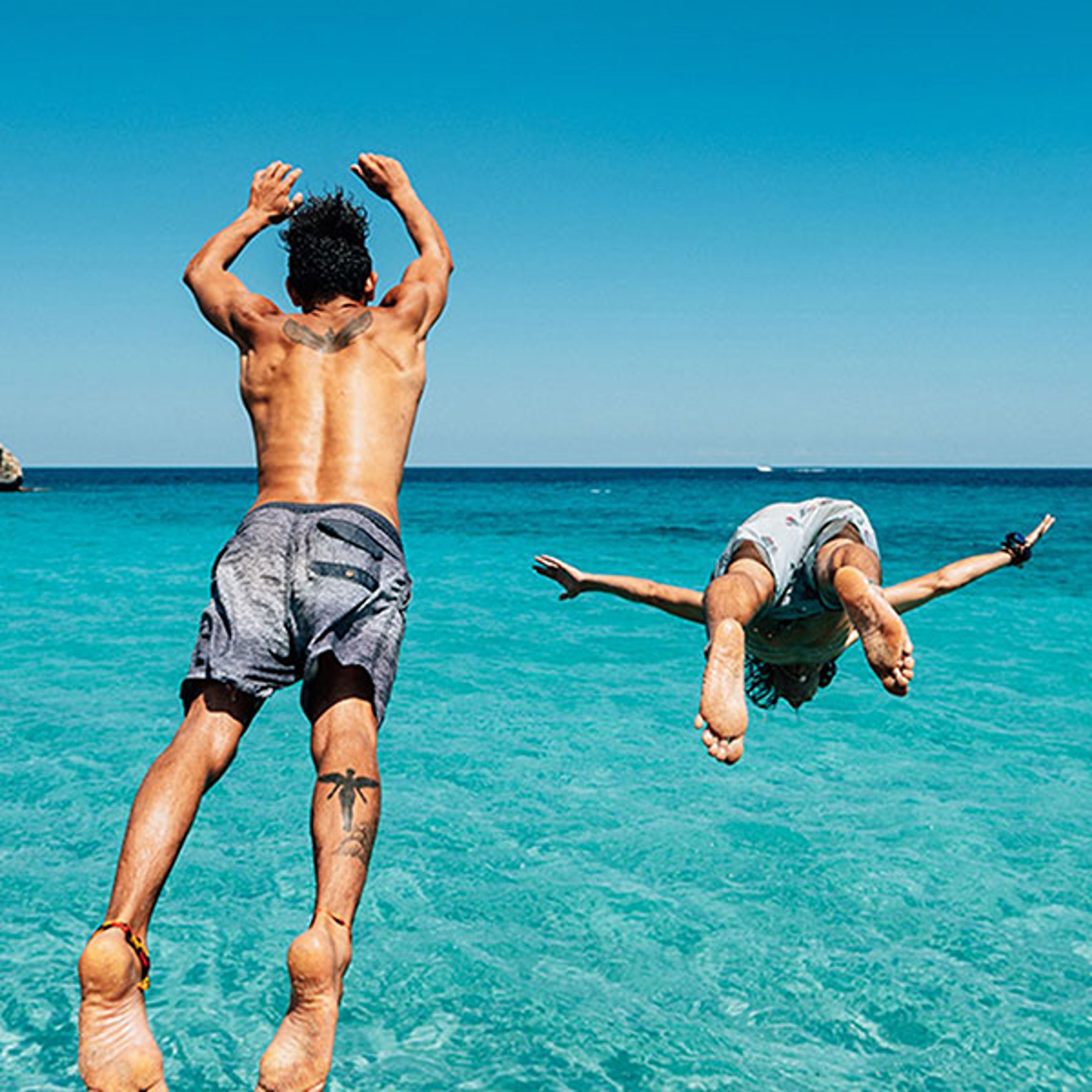 Teens diving into blue Caribbean ocean during spring break