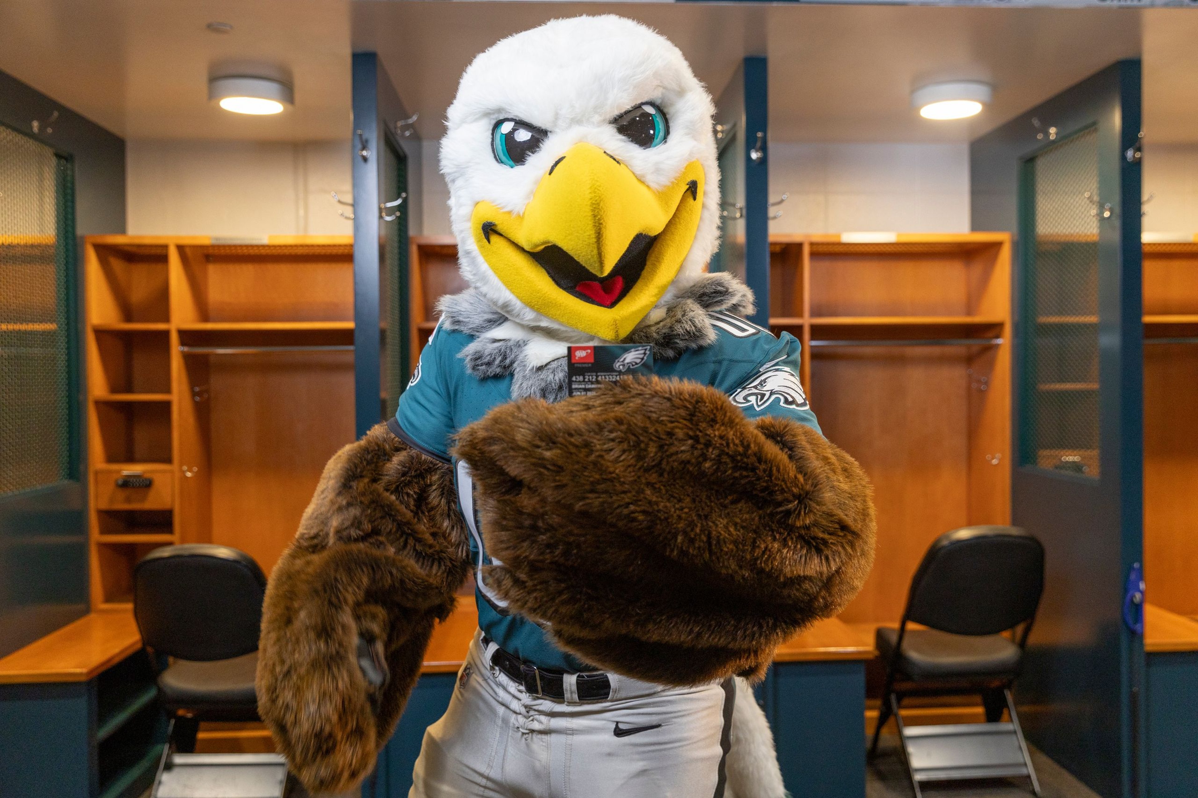 Philadelphia Eagles mascot Swoop holding Triple A Eagles MVP card in front of lockers