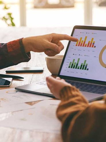 Business woman pointing to analytics on a laptop screen