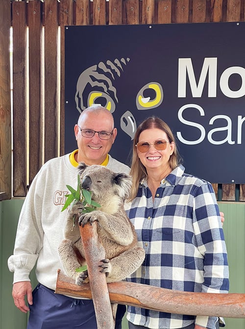 Martin Travel Exploring Australia NZ Koala Martin Travel Advisor Judy Miron and her husband posing with a koala eating eucalyptus at Moonlit Sanctuary in Melbourne, Australia