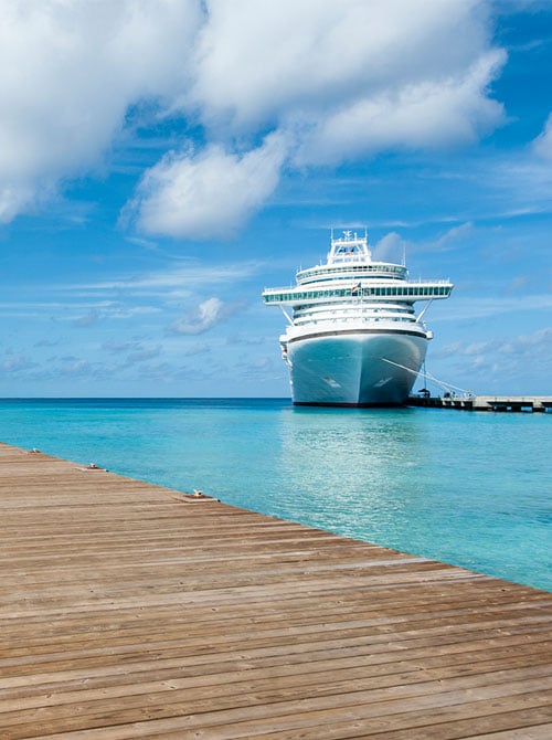 Tied up at the dock for a fun day ashore, a gleaming white cruise ship sparkles against a backdrop of blue skies and a dazzling turquoise sea.