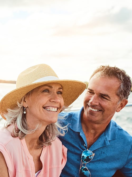 A happy, mature couple enjoys a sunny day while sitting on a boat or yacht